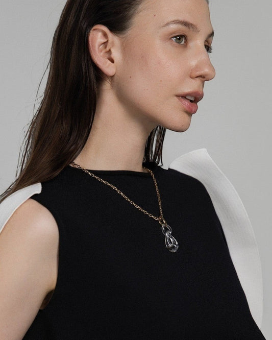 Elsita Jewelry Link Clear necklace featuring a hand-carved interlocked clear quartz pendant on a gold-tone chain.