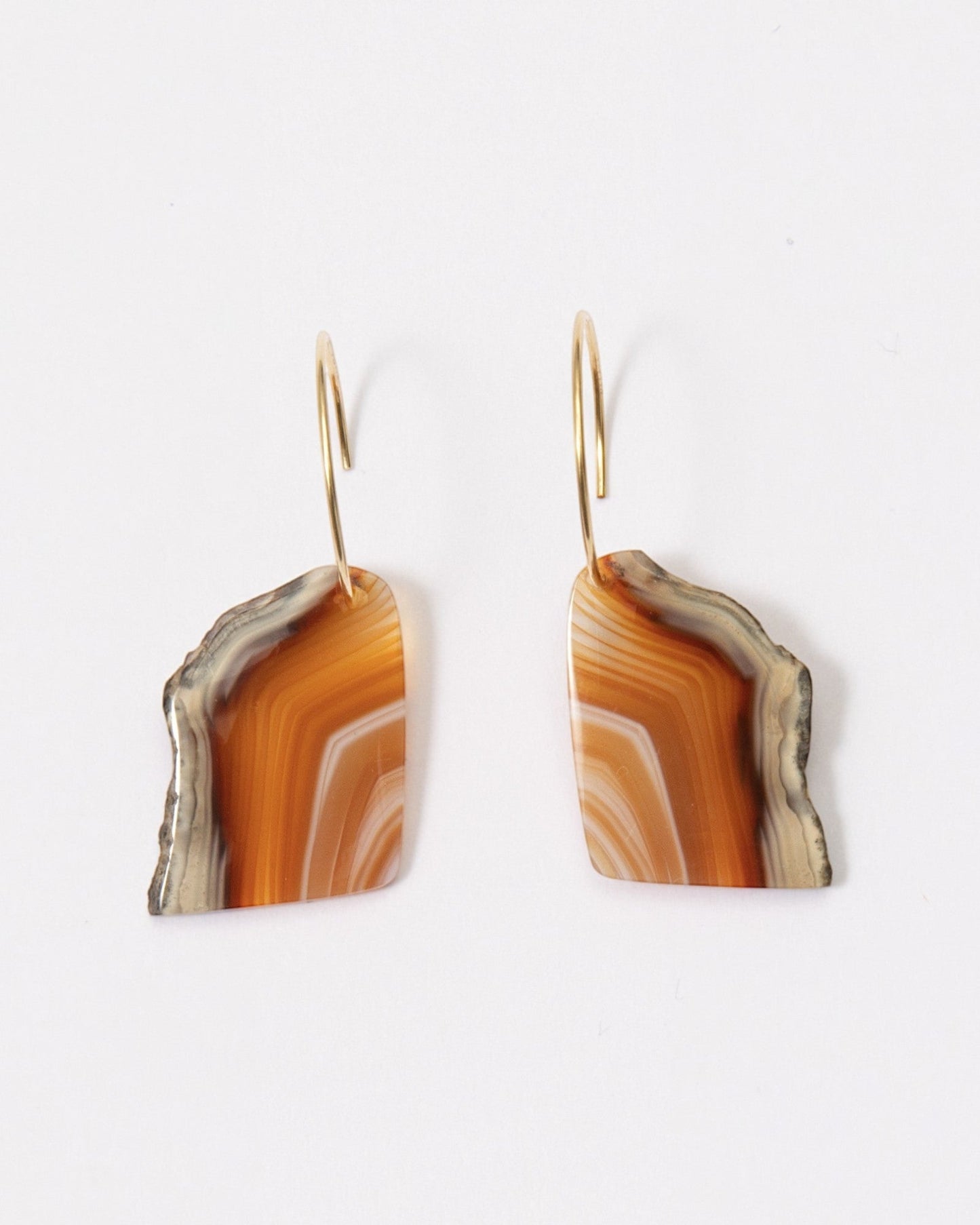 Elsita Jewelry Wild 7 agate earrings featuring freeform, banded orange and brown stone slices on 14K gold-filled hoops.