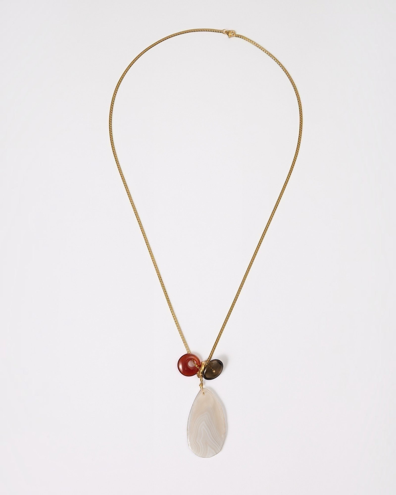 Elsita Jewelry Glacier Day necklace featuring a white agate slice, red agate ring, and smoky quartz on a gold chain.
