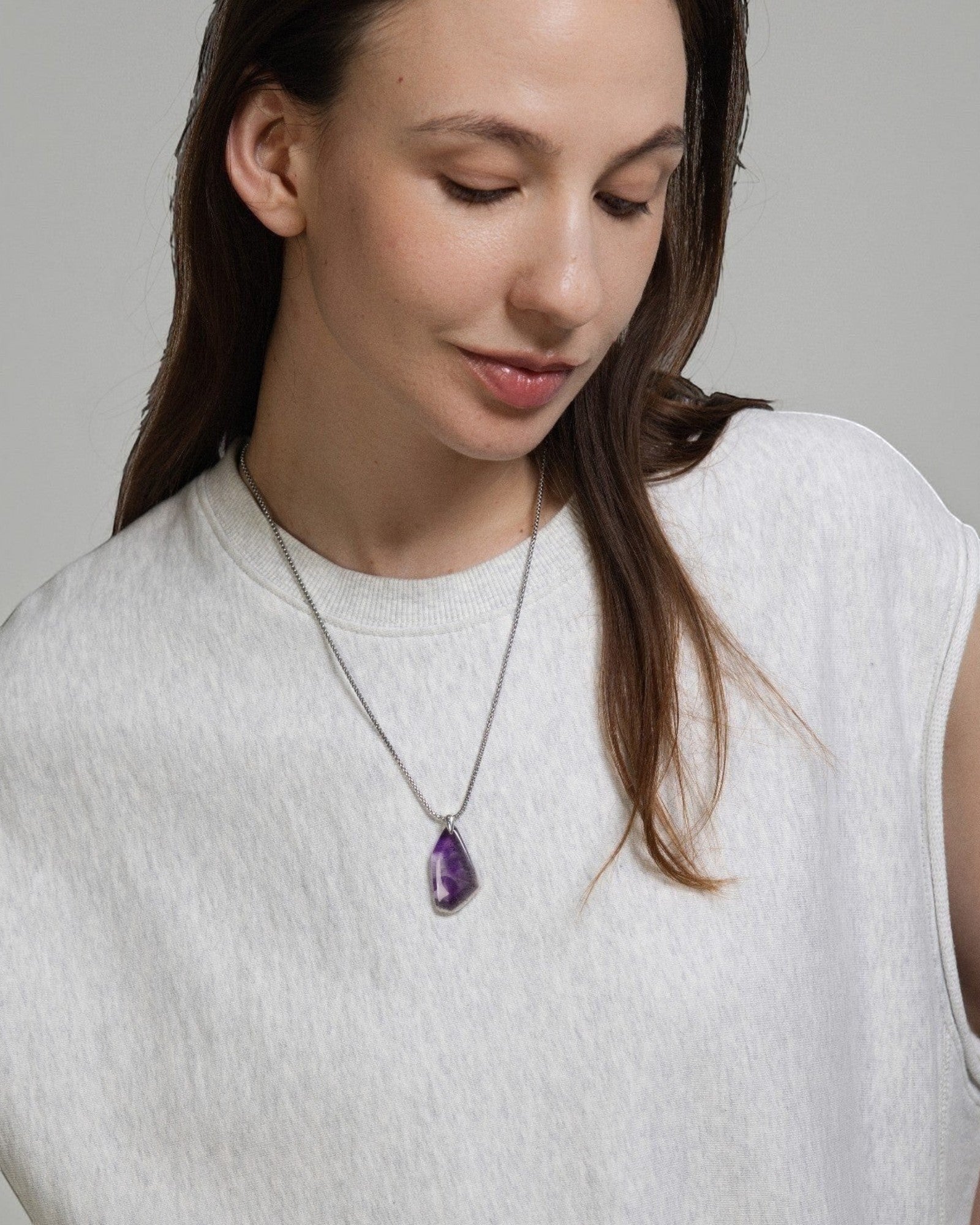 Model wearing an Elsita Jewelry amethyst pendant necklace with a raw crystal edge and sterling silver bail.