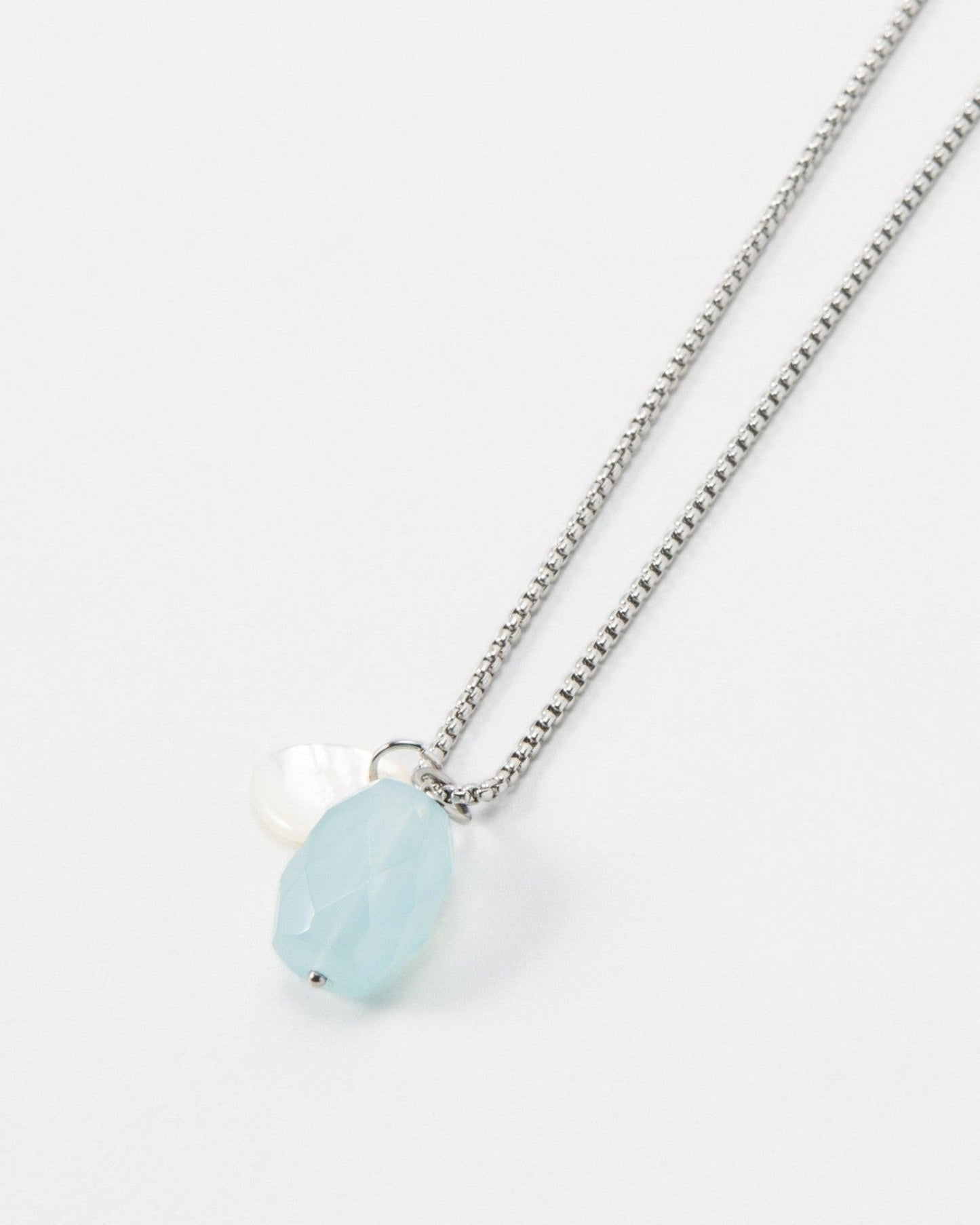 Elsita Jewelry Azul necklace featuring a light blue faceted gemstone and a small white pearl on a silver chain.