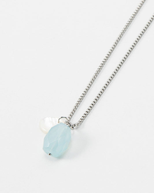 Elsita Jewelry Azul necklace featuring a light blue faceted gemstone and a small white pearl on a silver chain.