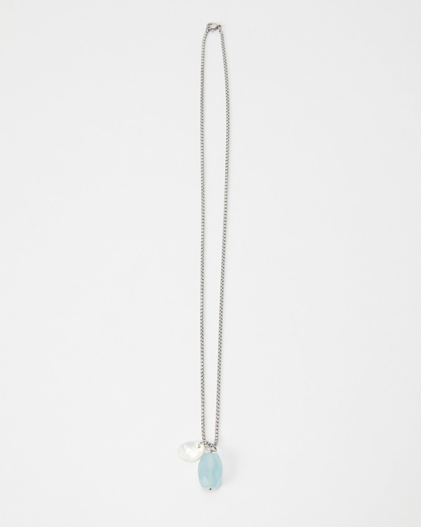 Elsita Jewelry Azul necklace featuring a light blue faceted gemstone and a small white pearl charm on a silver chain
