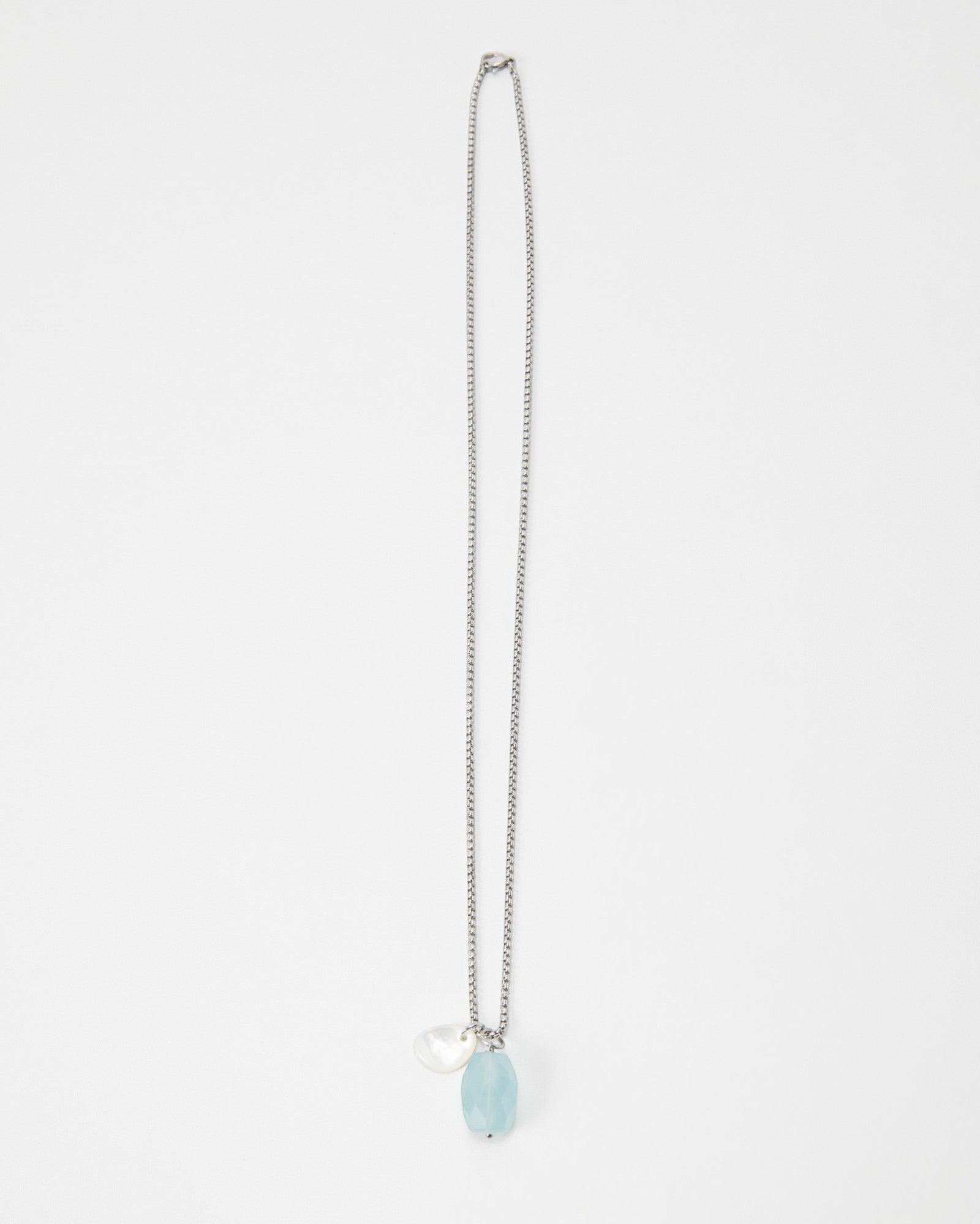 Elsita Jewelry Azul necklace featuring a light blue faceted gemstone and a small white pearl charm on a silver chain