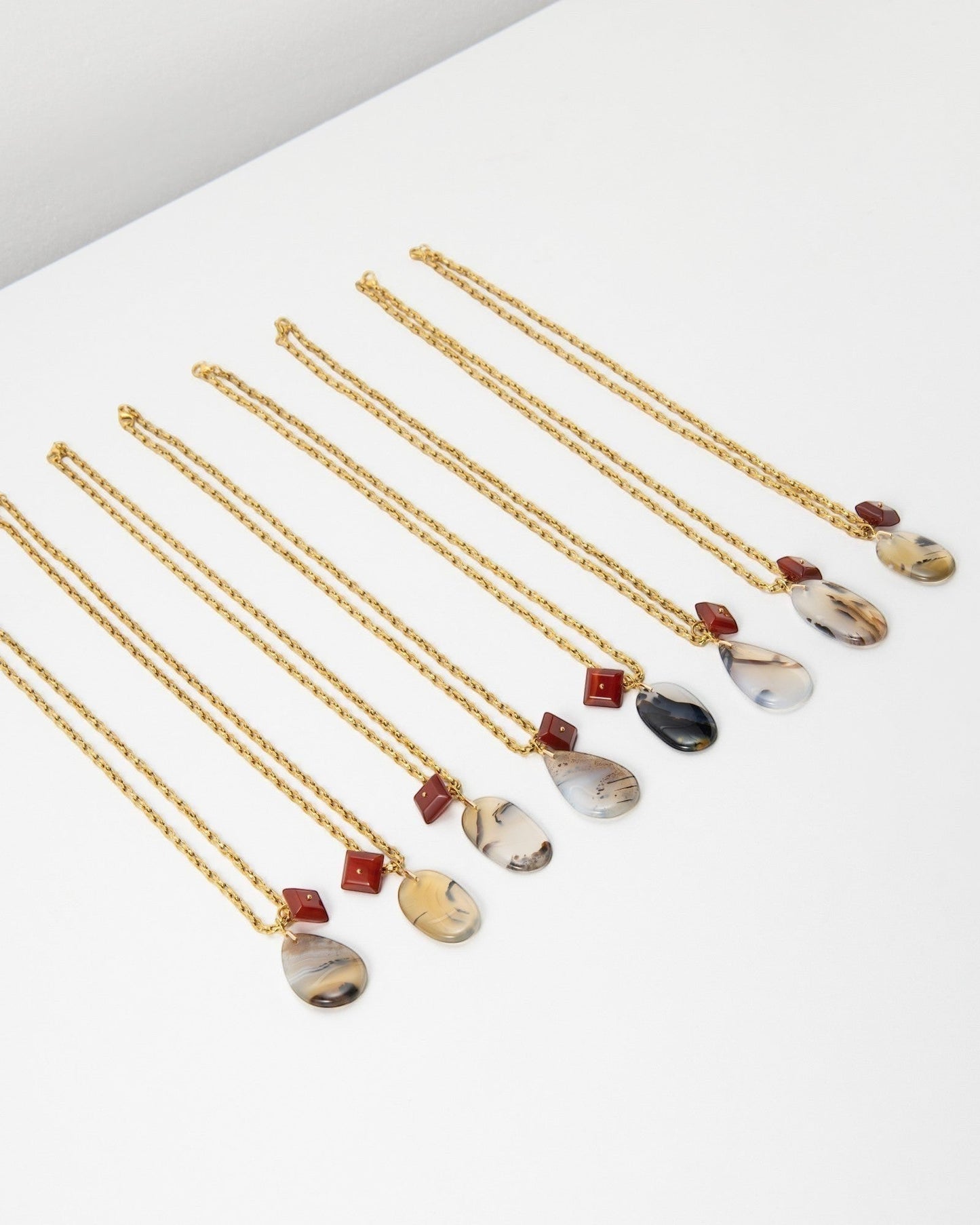 Elsita Jewelry Calligraphy necklaces featuring teardrop-shaped agate pendants and small square red stone accents.