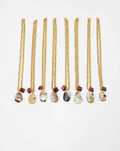 Elsita Jewelry Calligraphy necklaces featuring teardrop-shaped agate pendants and small red beads on gold chains.