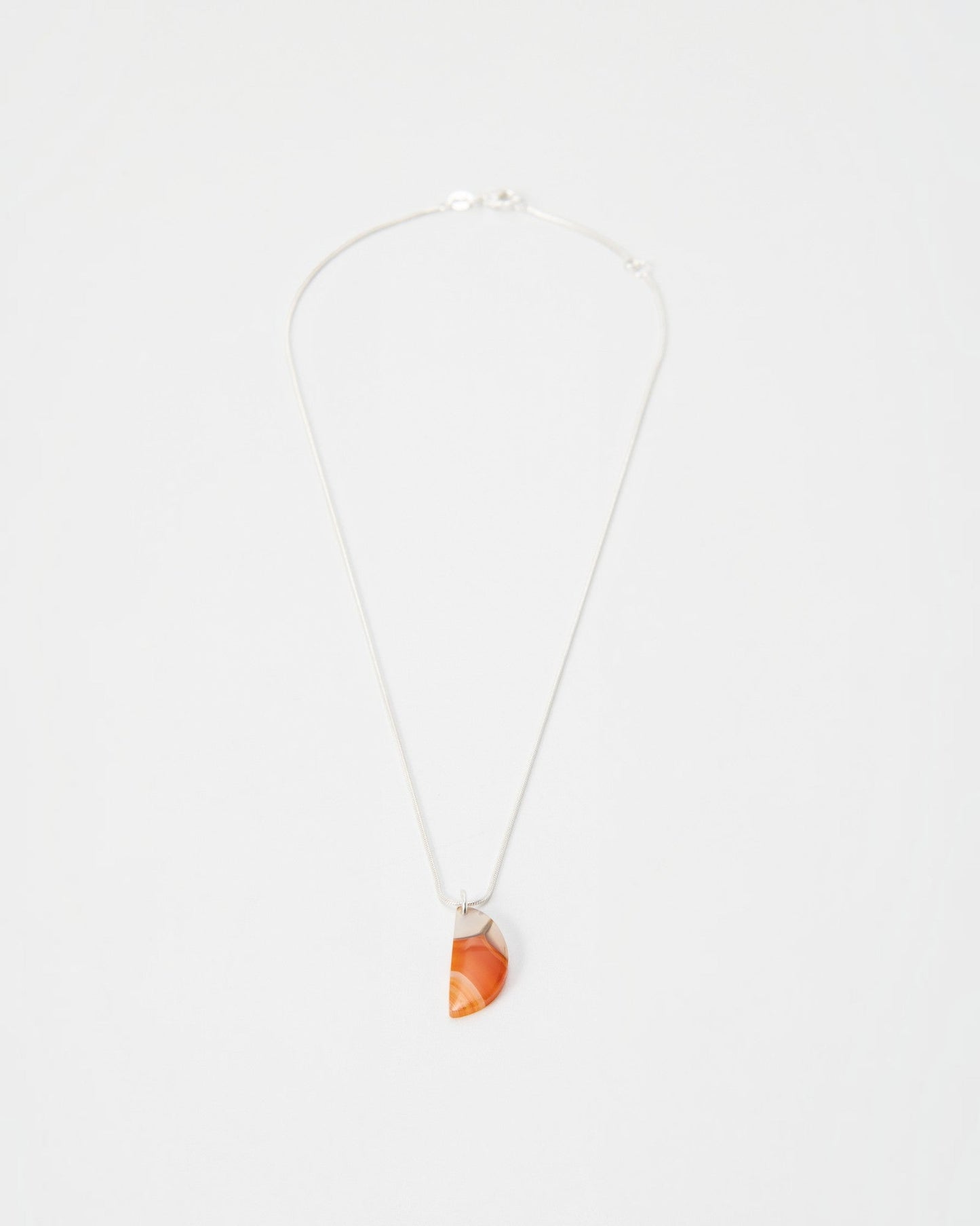 Elsita Jewelry Citrus I necklace featuring a semi-circular orange agate pendant on a delicate silver chain