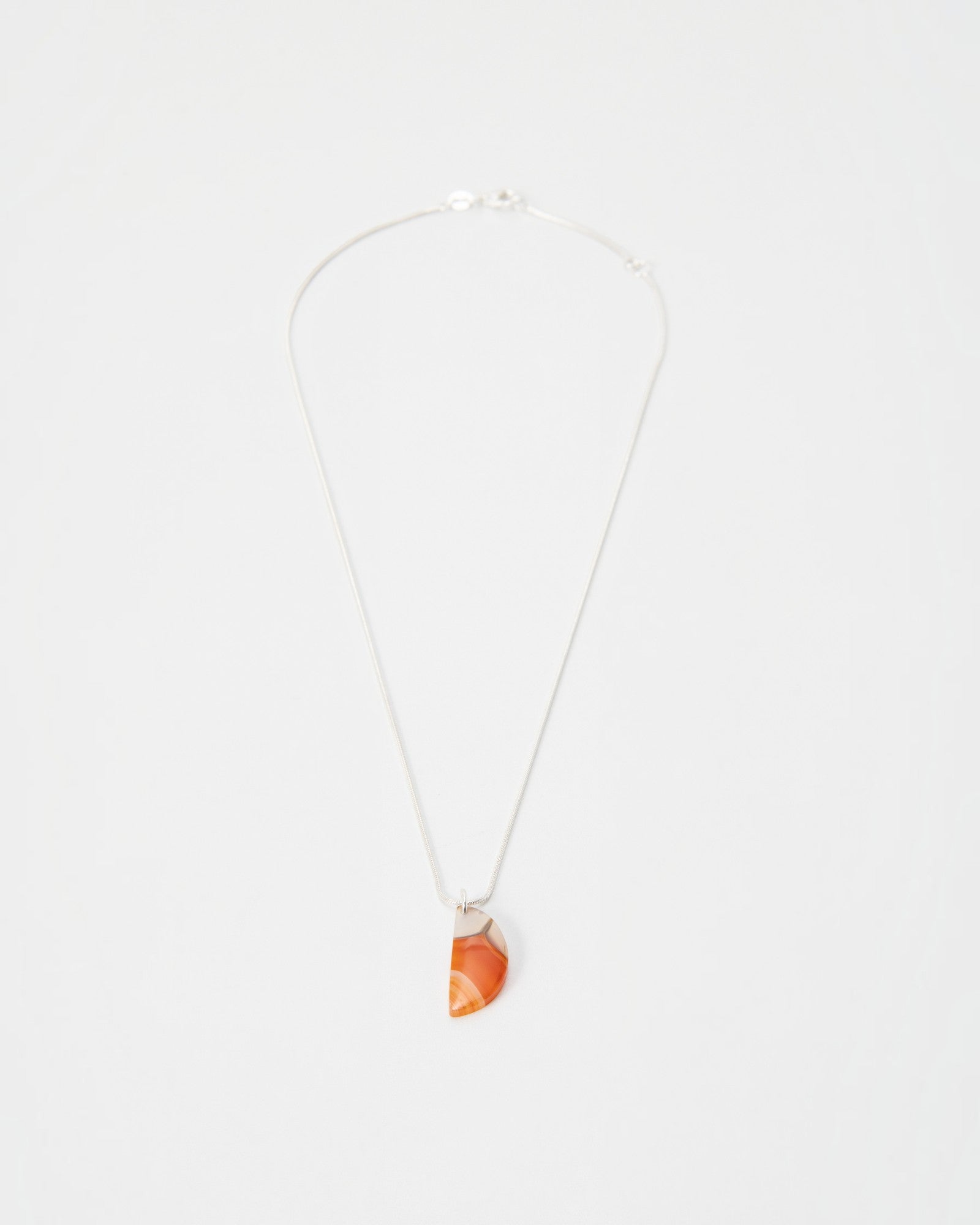 Elsita Jewelry Citrus I necklace featuring a semi-circular orange agate pendant on a delicate silver chain