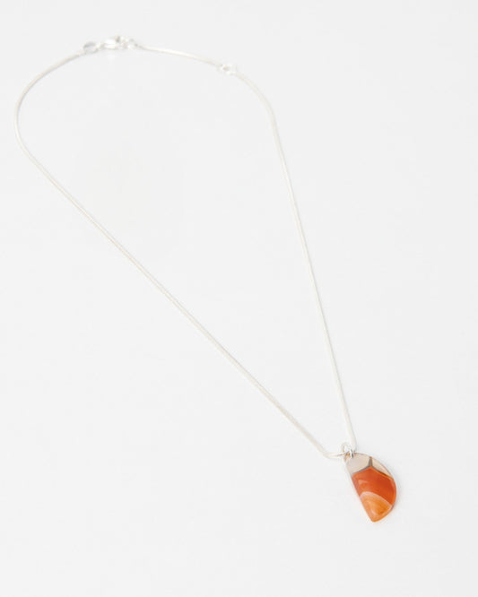 Elsita Jewelry Citrus I necklace featuring a small, semi-circular orange carnelian stone pendant on a silver chain.