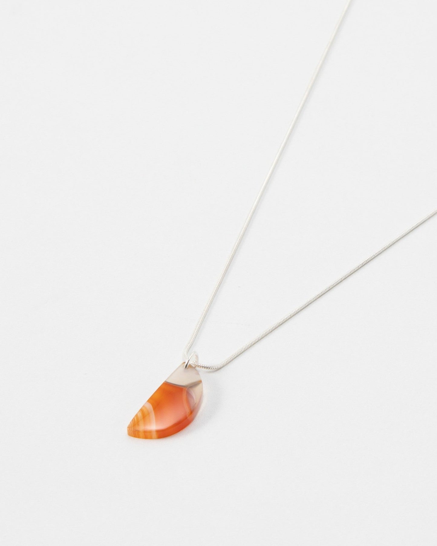 Elsita Jewelry Citrus I necklace featuring a semi-circular orange carnelian stone pendant on a delicate silver chain.