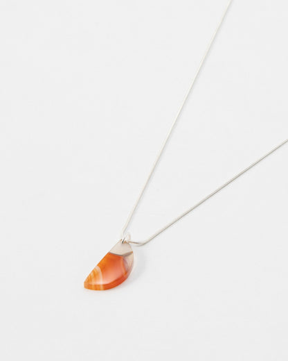 Elsita Jewelry Citrus I necklace featuring a semi-circular orange carnelian stone pendant on a delicate silver chain.