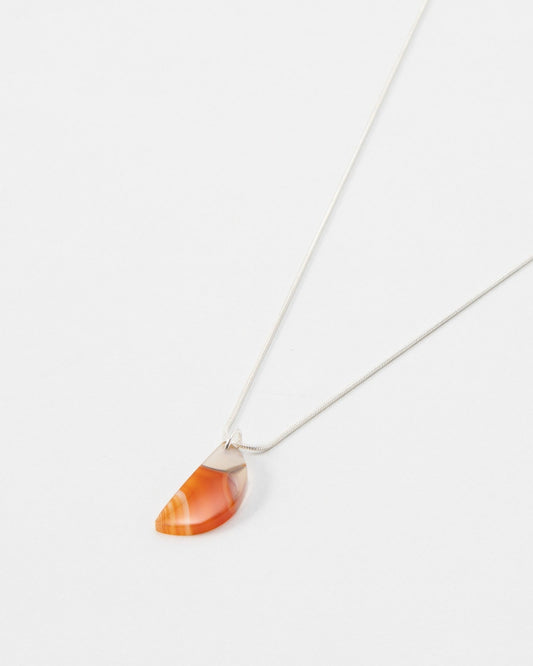 Elsita Jewelry Citrus I necklace featuring a semi-circular orange carnelian stone pendant on a delicate silver chain.