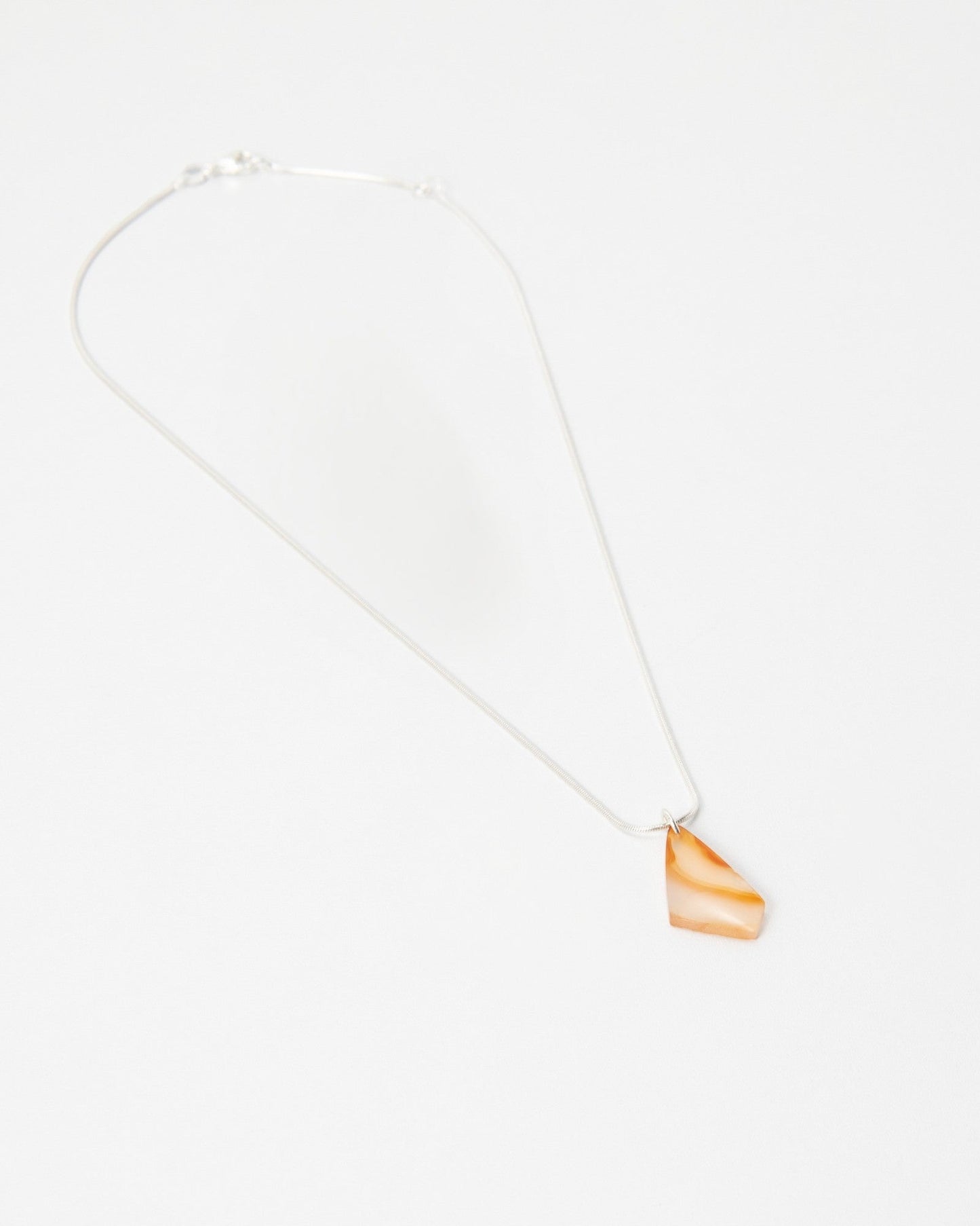 Elsita Jewelry Citrus II necklace featuring a delicate silver chain and a small, translucent orange stone pendant.