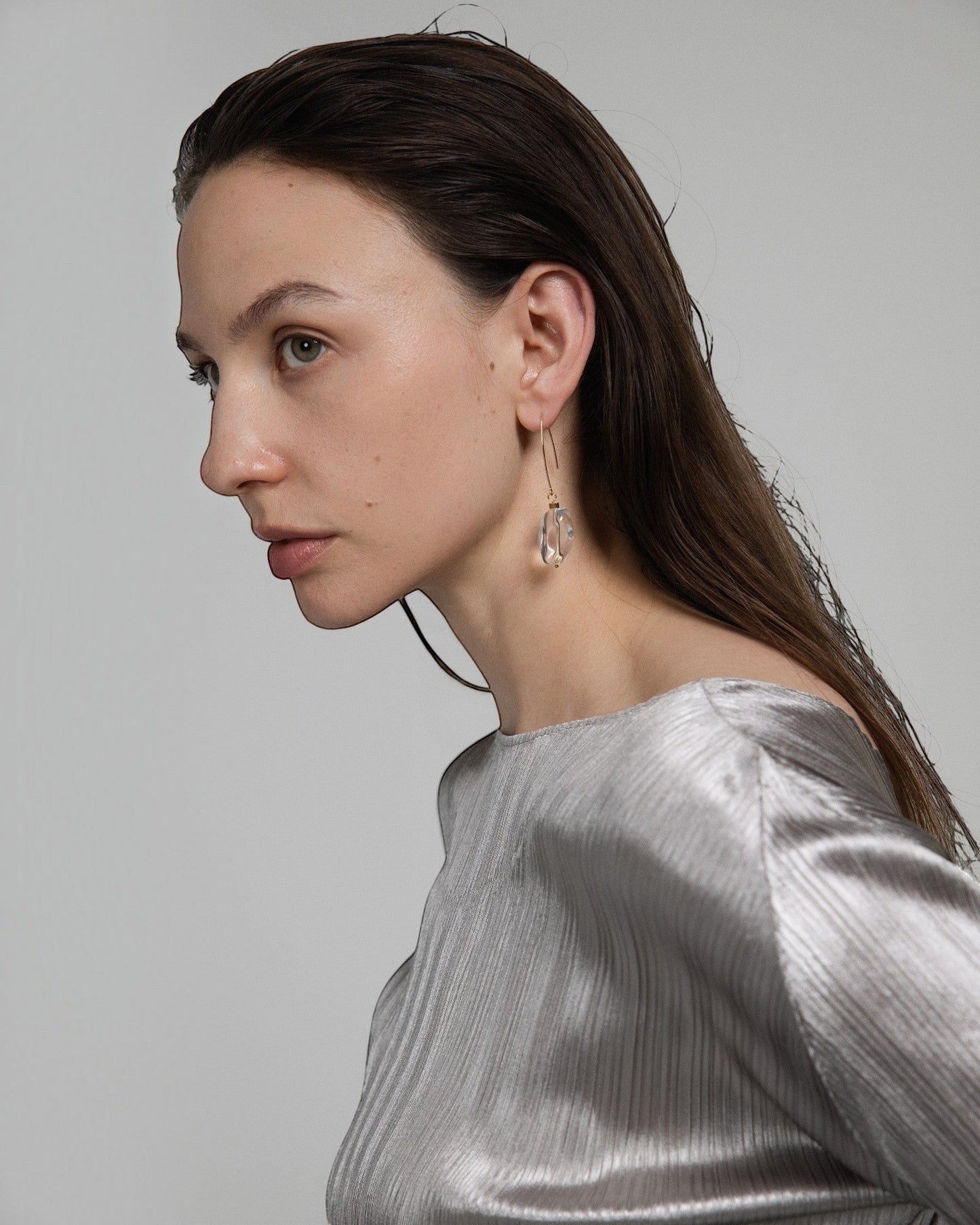 Model wearing Elsita Jewelry faceted clear quartz drop earrings with 14K gold-filled hooks and stainless steel beads.