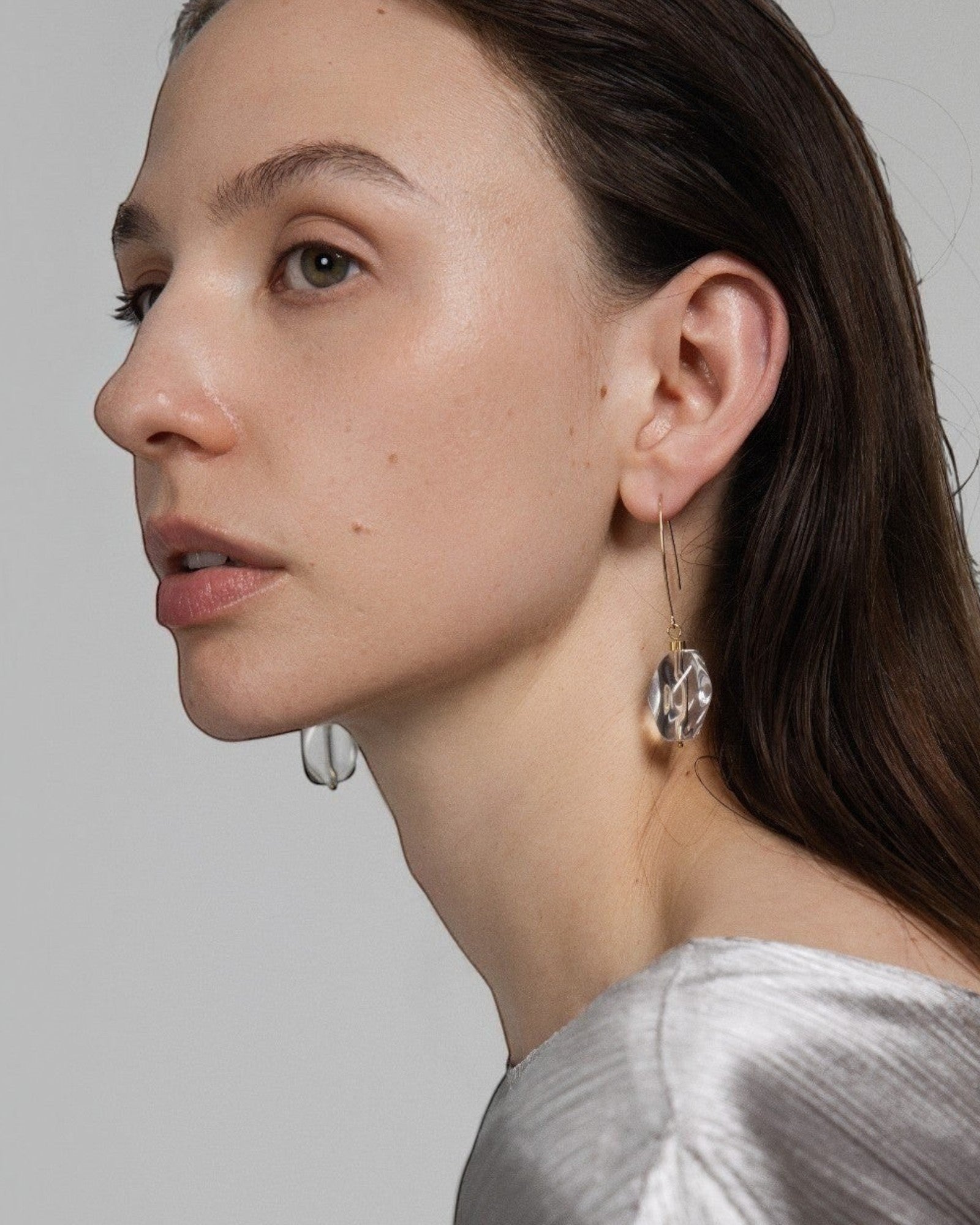 Model wearing Elsita Jewelry faceted clear quartz drop earrings with 14K gold-filled hooks and stainless-steel beads.