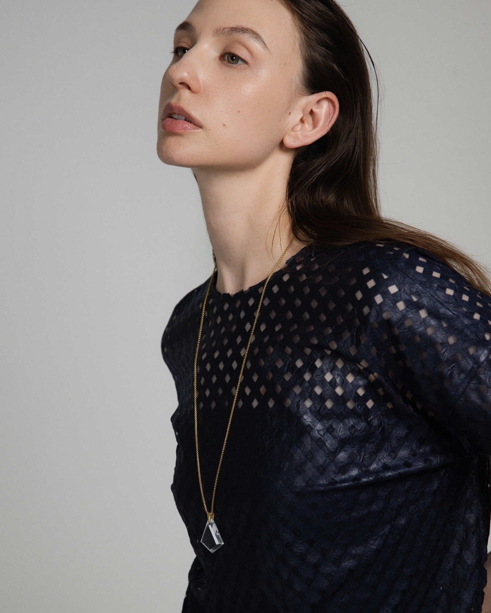 Model wearing an Elsita Jewelry Lustre III clear quartz pendant necklace on a gold-tone stainless steel chain.