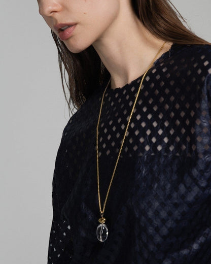 Model wearing an Elsita Jewelry Lustre I necklace featuring a clear quartz pendant on a gold-tone stainless steel chain.