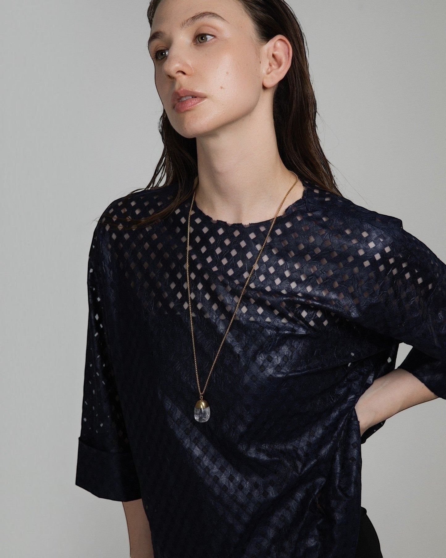 Elsita Jewelry Lustre IV necklace featuring a clear quartz pendant with gold-toned stainless steel on a long chain.