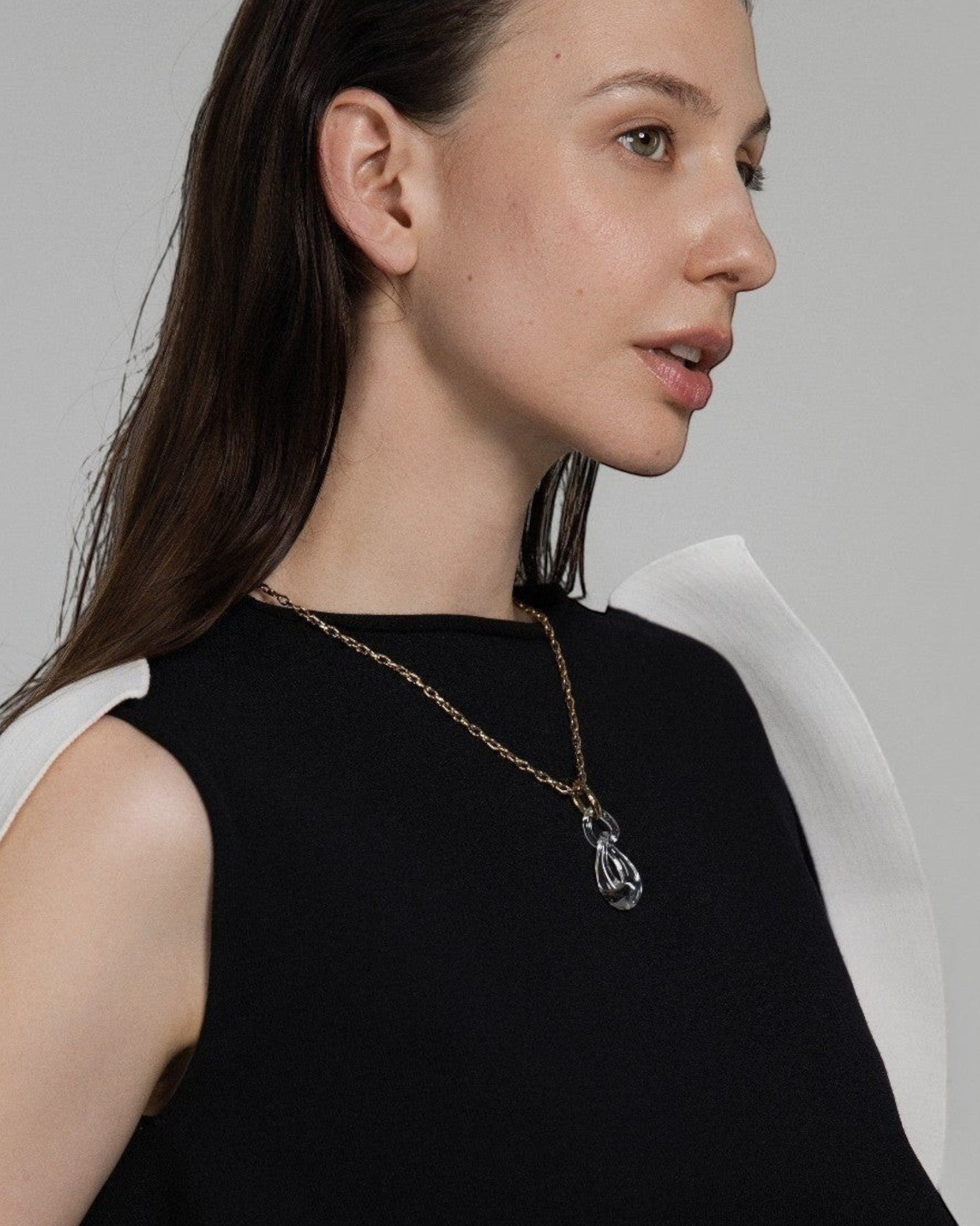 Elsita Jewelry Link Clear necklace featuring a hand-carved interlocked clear quartz pendant on a gold-tone chain.