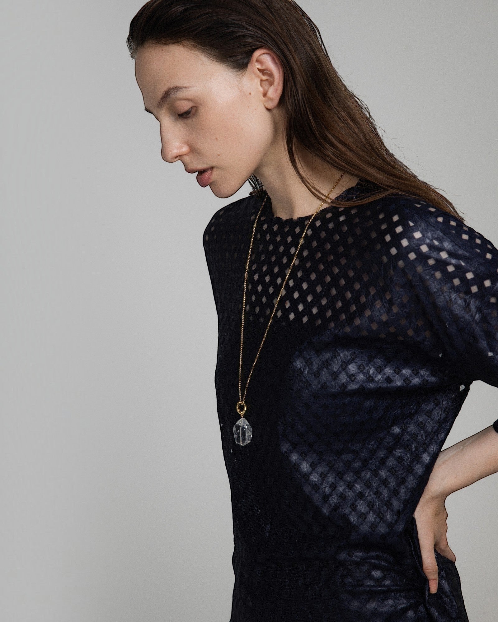 Model wearing an Elsita Jewelry Lustre II clear quartz pendant necklace on a gold-tone chain with a dark textured top