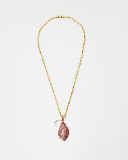 Elsita Jewelry Drift necklace featuring a gold chain with a teardrop-shaped pink stone and a small clear crystal charm.