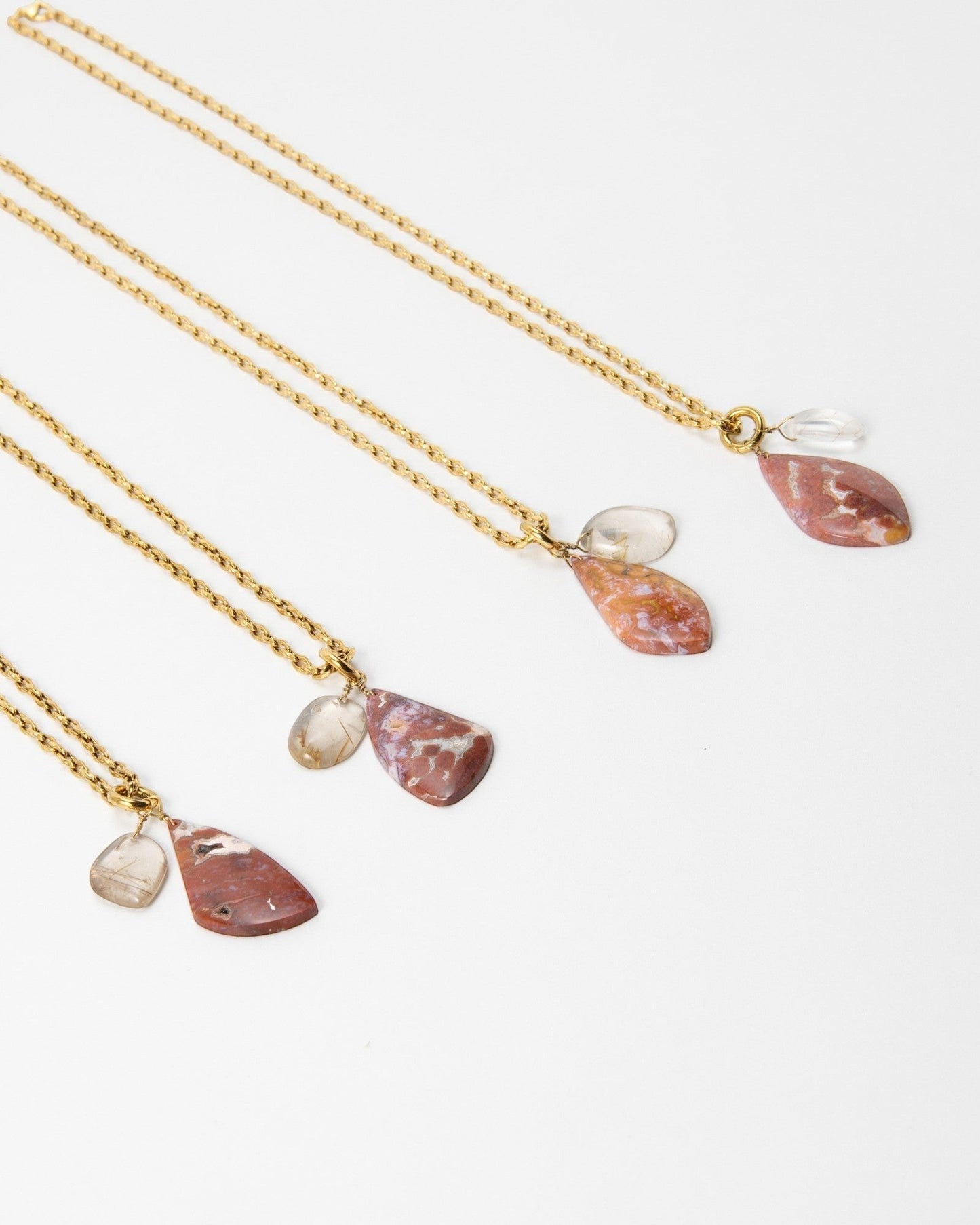 Elsita Jewelry Drift necklaces featuring gold chains with teardrop-shaped red jasper and clear quartz pendants.