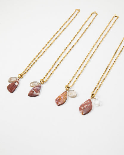 Elsita Jewelry Drift necklaces featuring gold chains with dangling red jasper and clear quartz stone pendants.