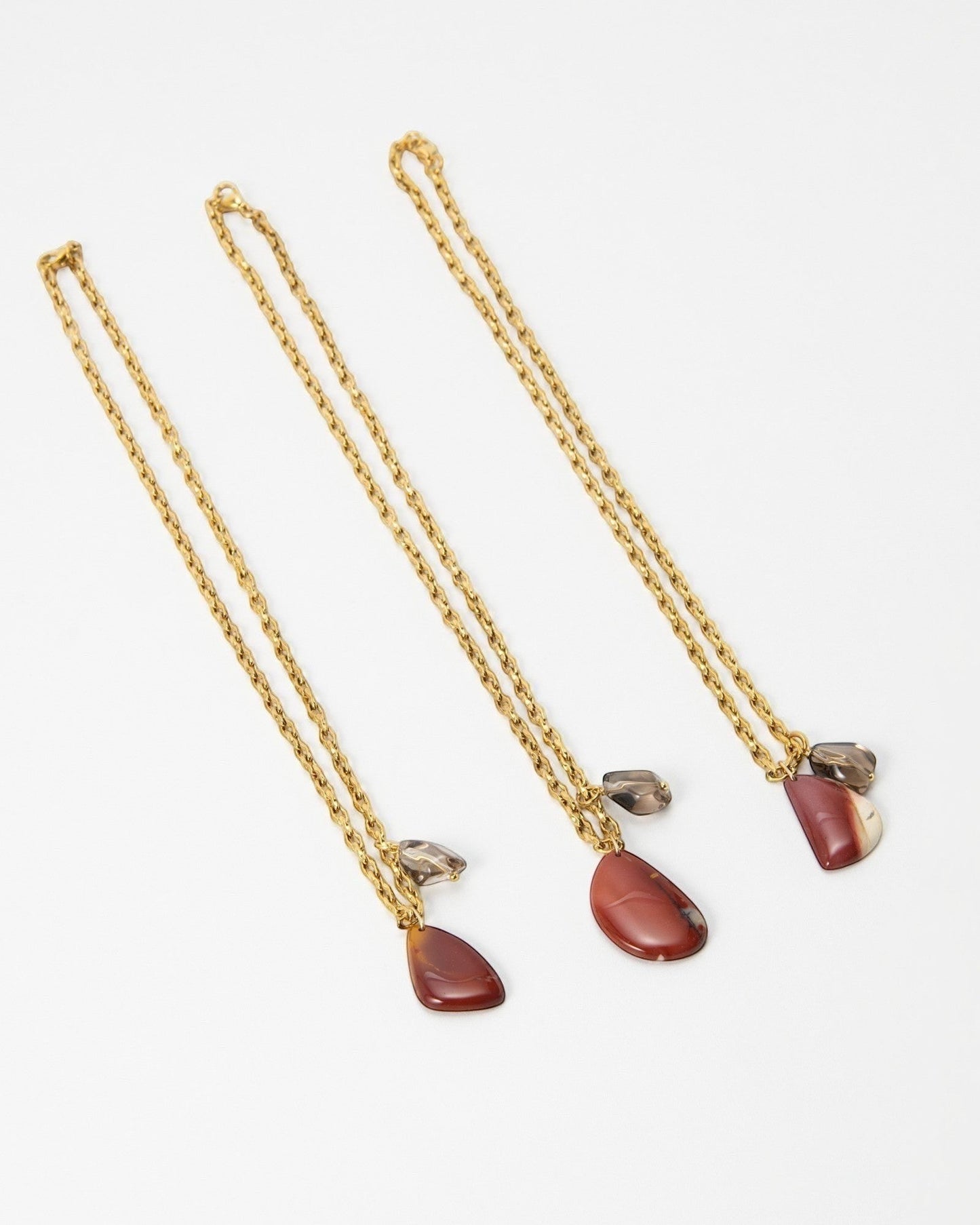 Elsita Jewelry Ember necklaces featuring gold chains with red jasper and smoky quartz gemstone pendants