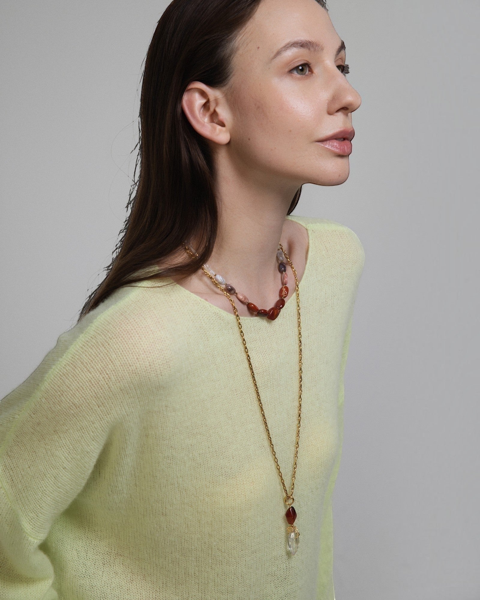 Elsita Jewelry Flame necklace featuring clear quartz and red agate stones on a gold chain worn by a woman
