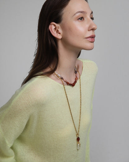 Elsita Jewelry Flame necklace featuring clear quartz and red agate stones on a gold chain worn by a woman