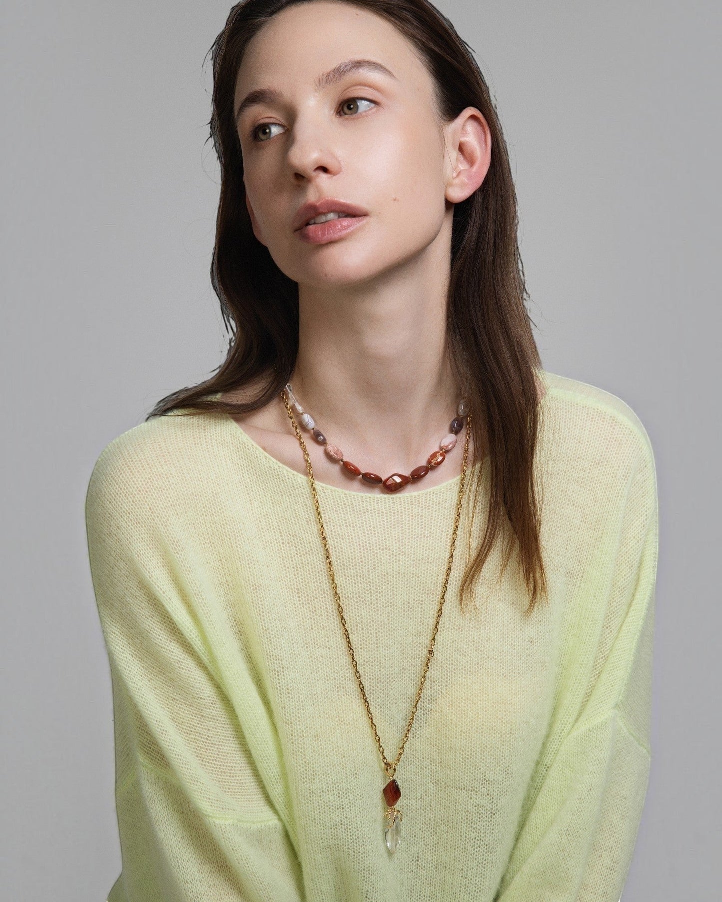Elsita Jewelry Flame necklace featuring a clear quartz and red agate pendant on a gold chain worn by a model.