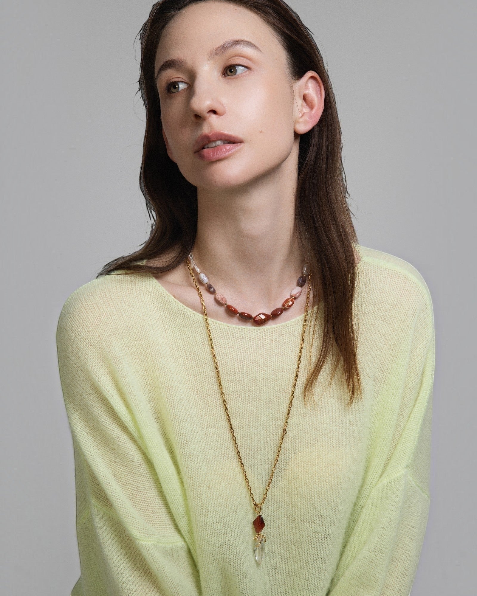 Elsita Jewelry Flame necklace featuring a clear quartz and red agate pendant on a gold chain worn by a model.