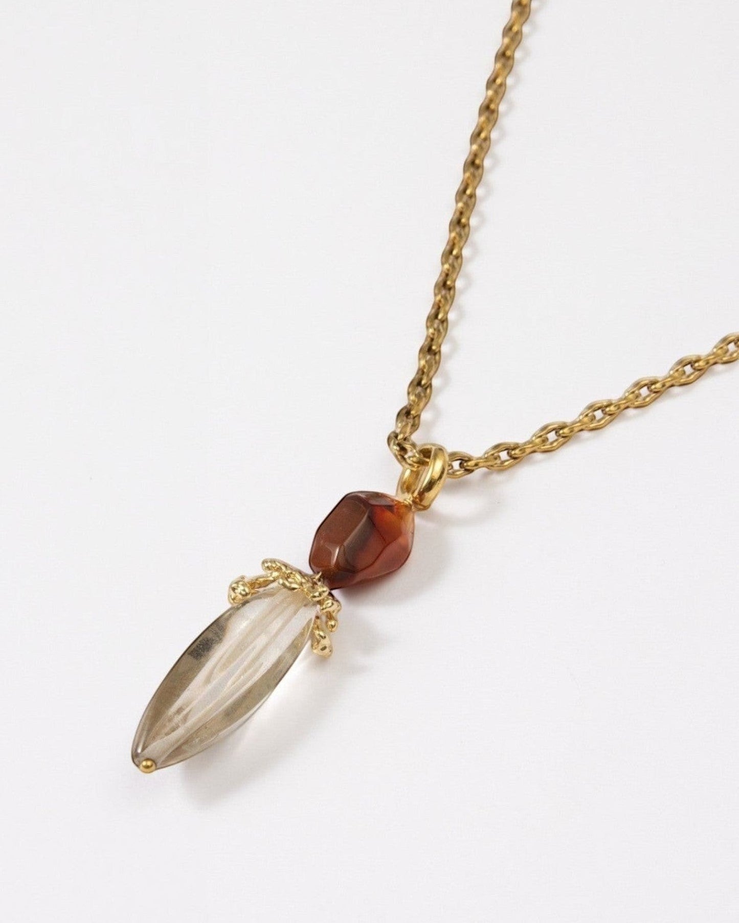 Elsita Jewelry Flame necklace featuring a clear quartz pendant and red agate on a textured gold chain.