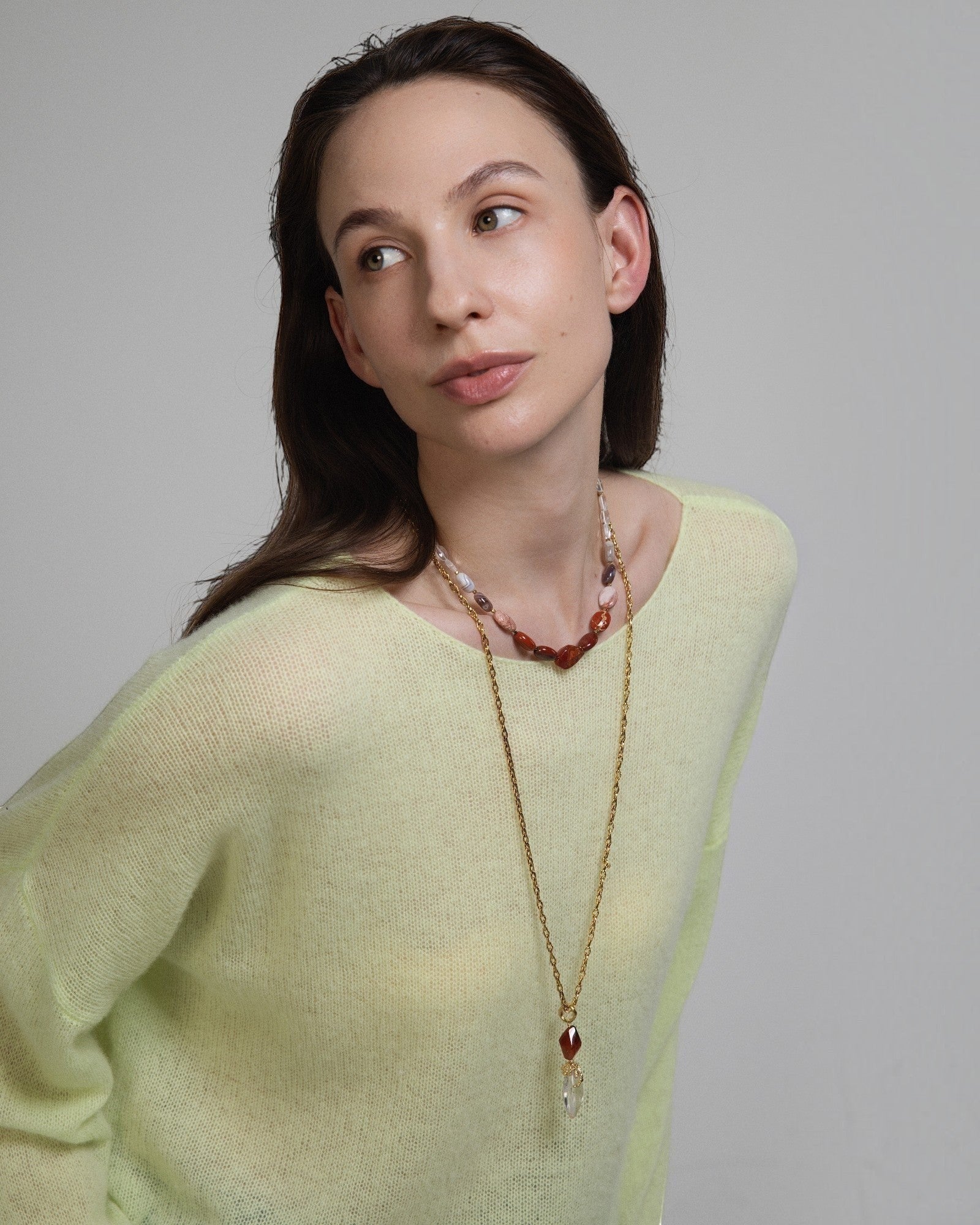 Elsita Jewelry Glow necklace featuring red agate, jasper, and clear quartz beads worn by a model in a yellow sweater