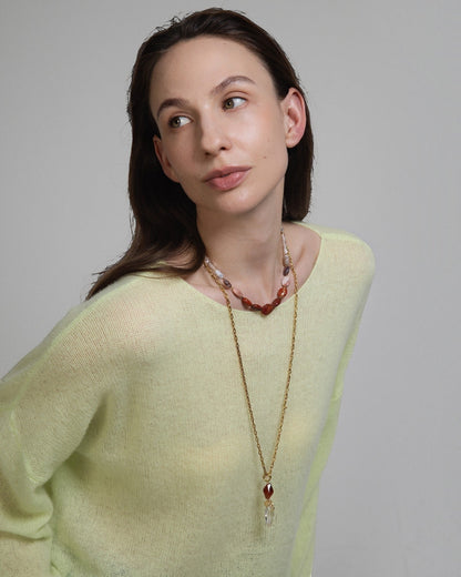 Elsita Jewelry Glow necklace featuring red agate, jasper, and clear quartz beads worn by a model in a yellow sweater
