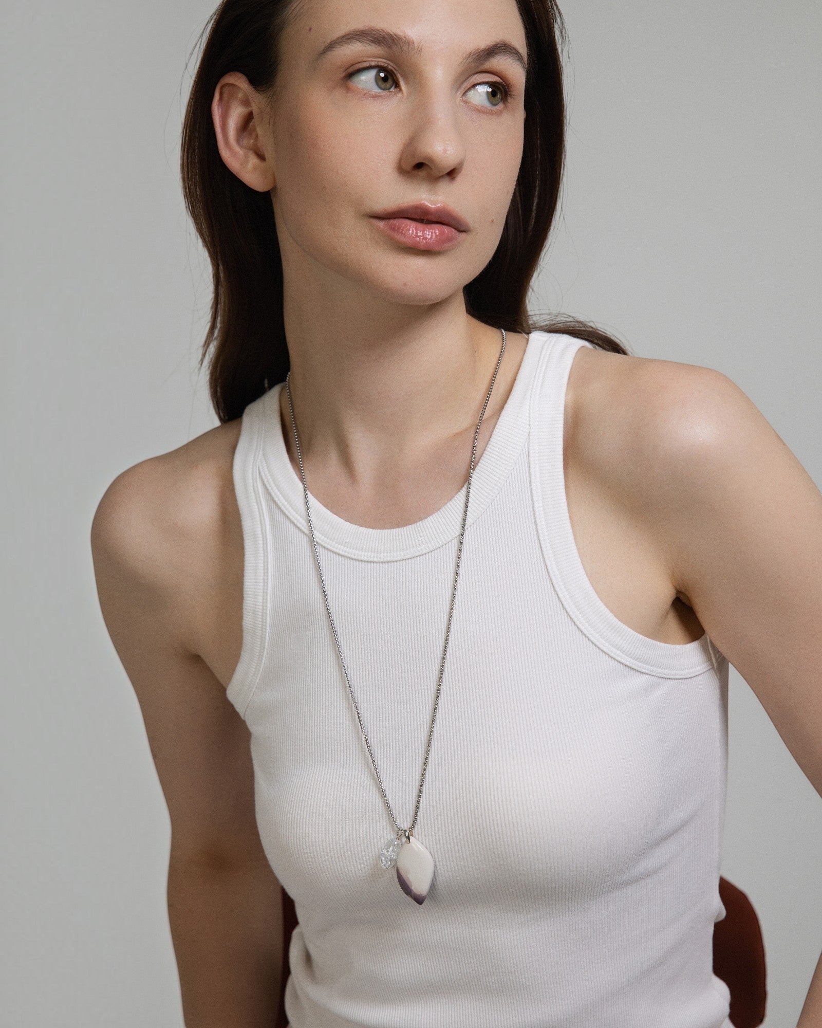 Model wearing an Elsita Jewelry Hyacinth Jasper pendant necklace with a clear quartz accent on a sterling silver chain.