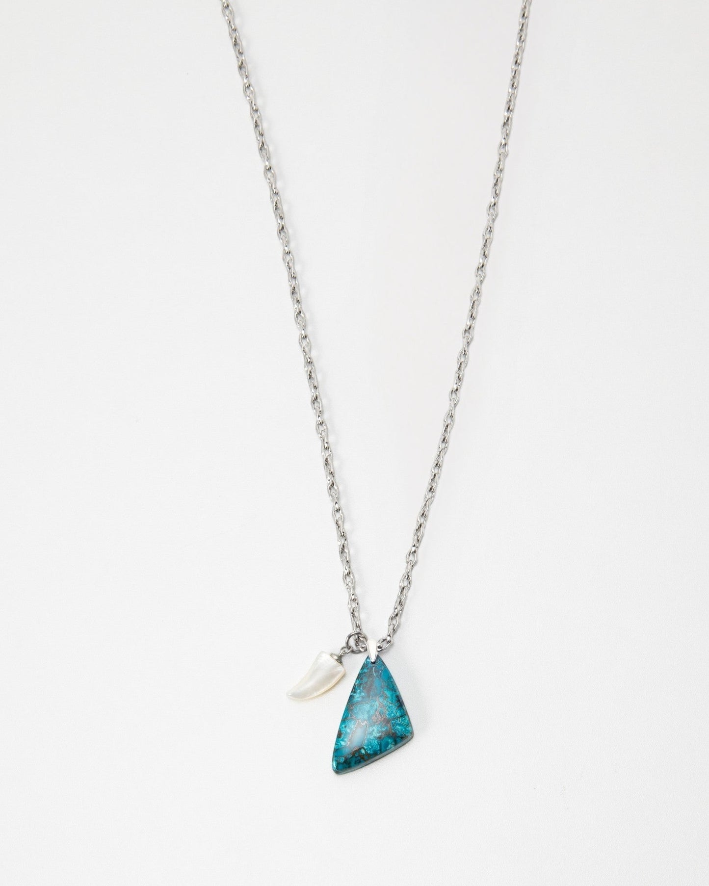 Elsita Jewelry Lagoon I necklace featuring a triangular blue stone pendant and a small white horn charm on a silver chain