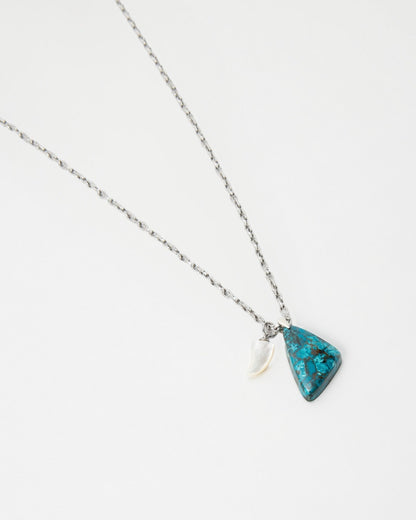 Elsita Jewelry Lagoon I necklace featuring a triangular blue stone pendant and a small white horn charm on a chain