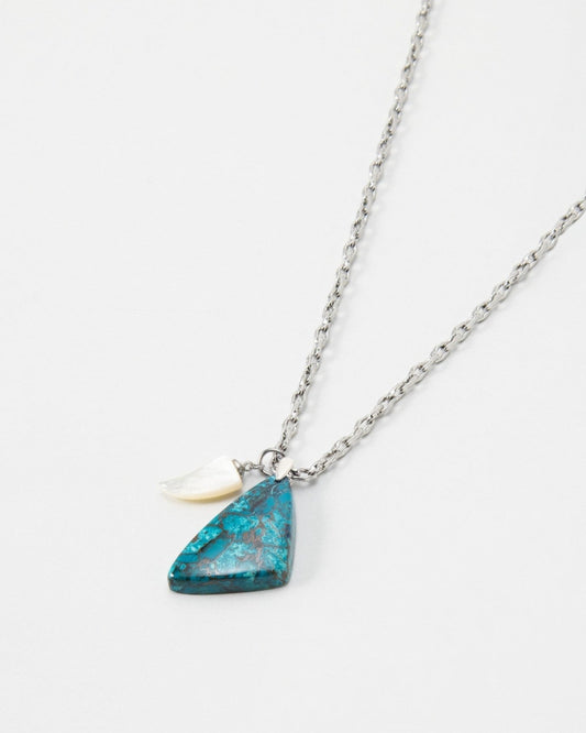 Elsita Jewelry Lagoon I necklace featuring a triangular blue stone pendant and a small white shell charm on a silver chain