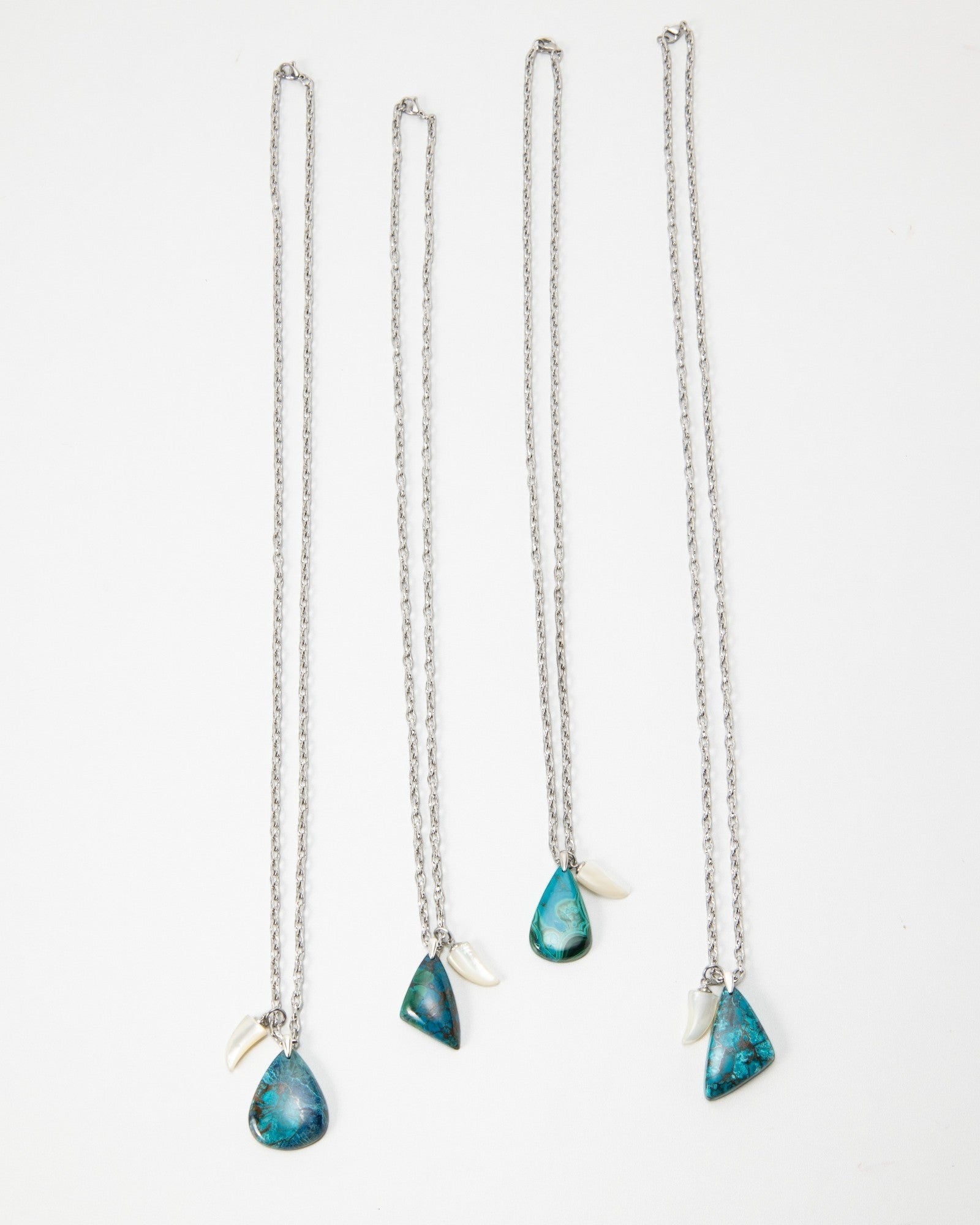 Elsita Jewelry Lagoon I necklaces featuring blue teardrop stones and white shell accents on silver chains.