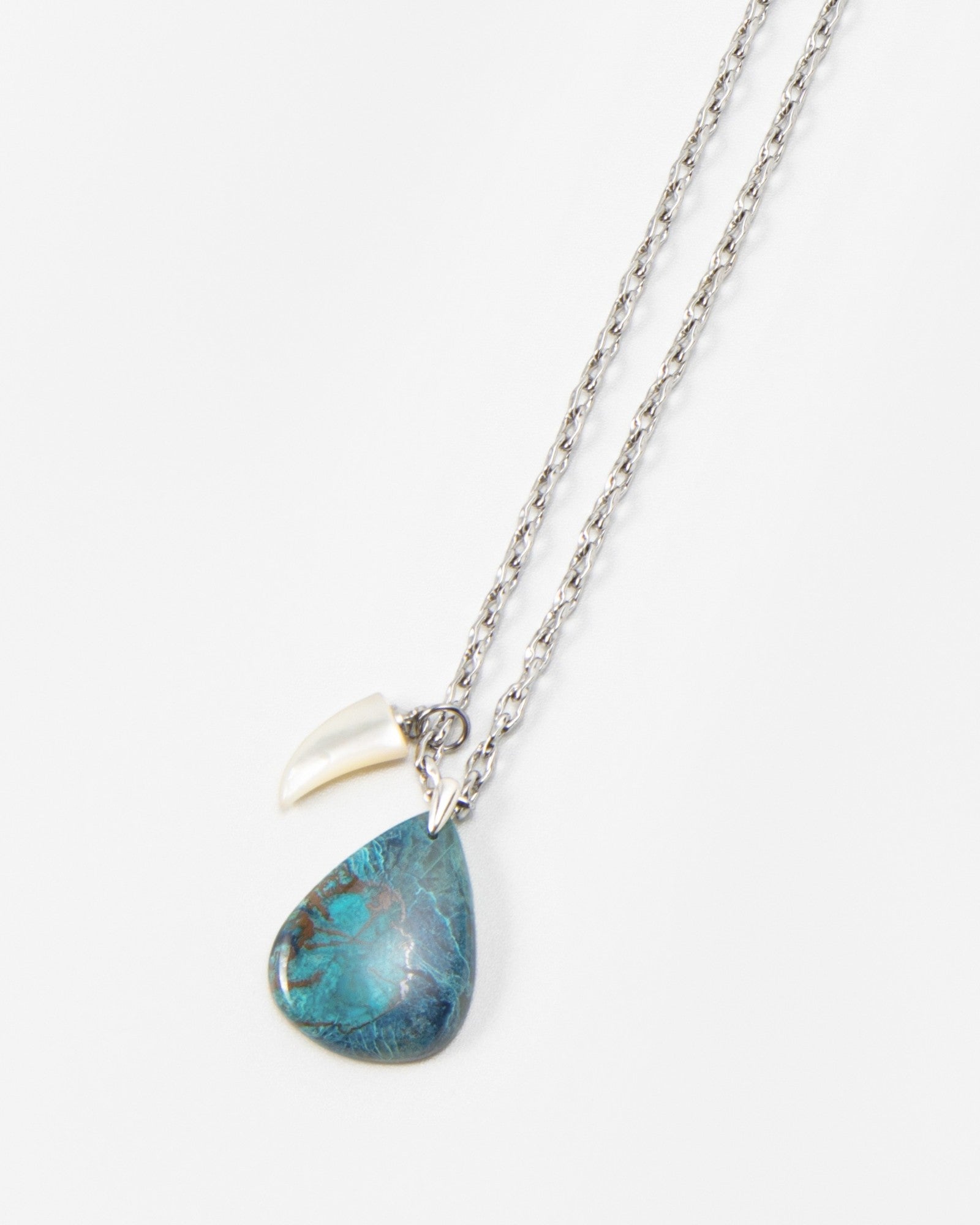 Elsita Jewelry Lagoon II necklace featuring a teardrop-shaped blue stone pendant and a small white charm on a silver chain