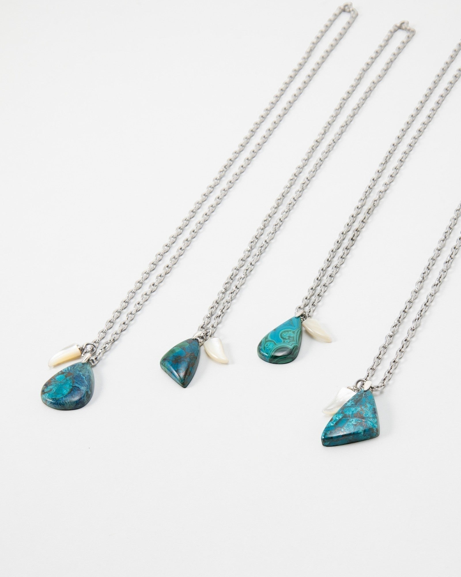 Four Elsita Jewelry Lagoon III necklaces featuring blue malachite pendants and small white shell accents on silver chains