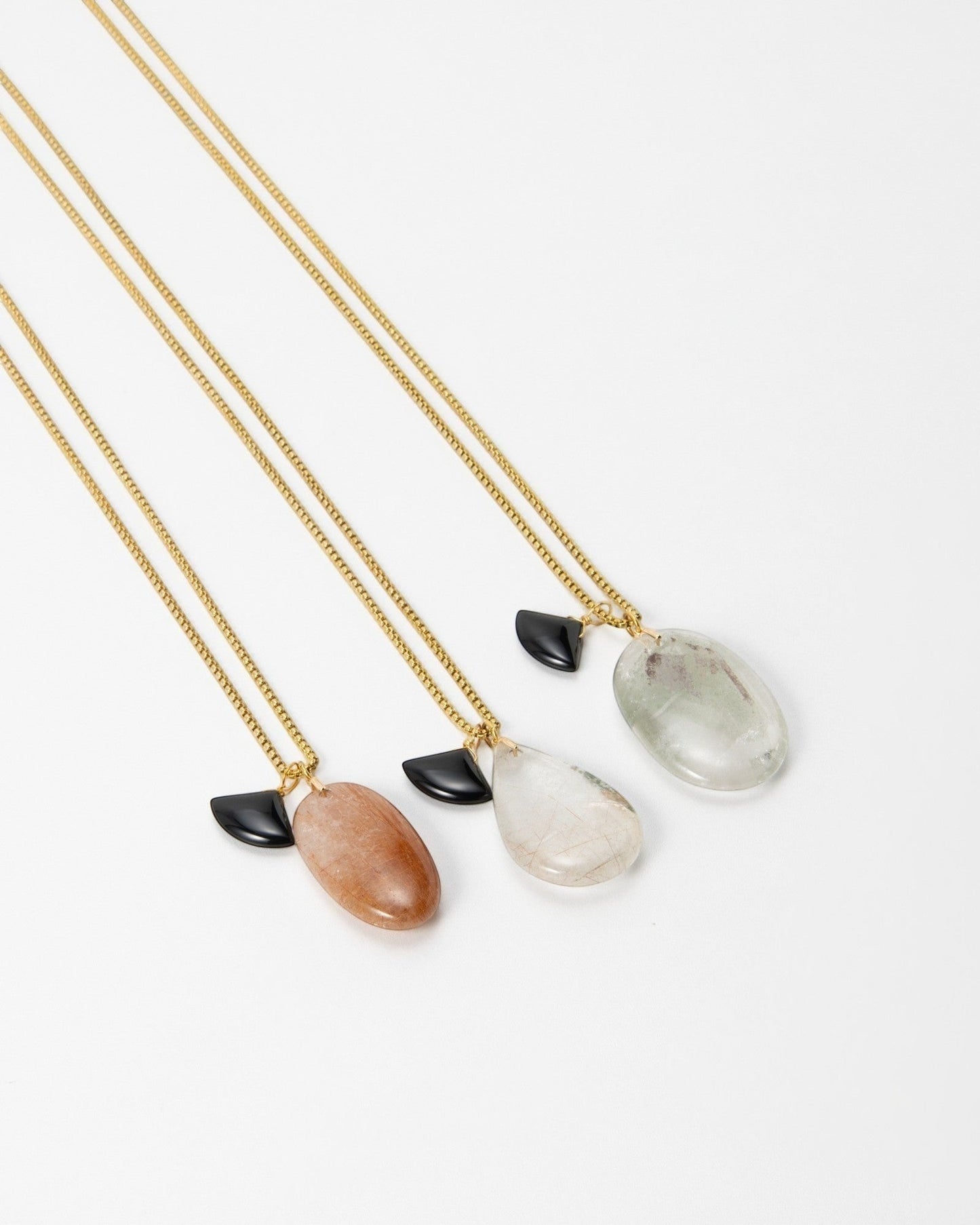 Elsita Jewelry Mist II necklaces featuring gold chains, polished gemstone pendants, and small black accent charms.