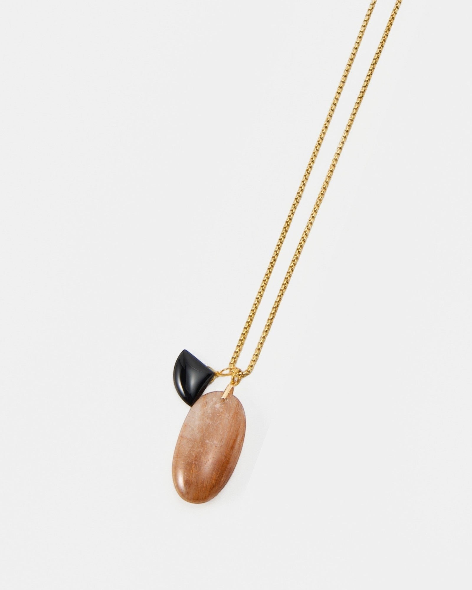 Elsita Jewelry Mist II necklace featuring a delicate gold chain with a black stone and a smooth peach-toned pendant.