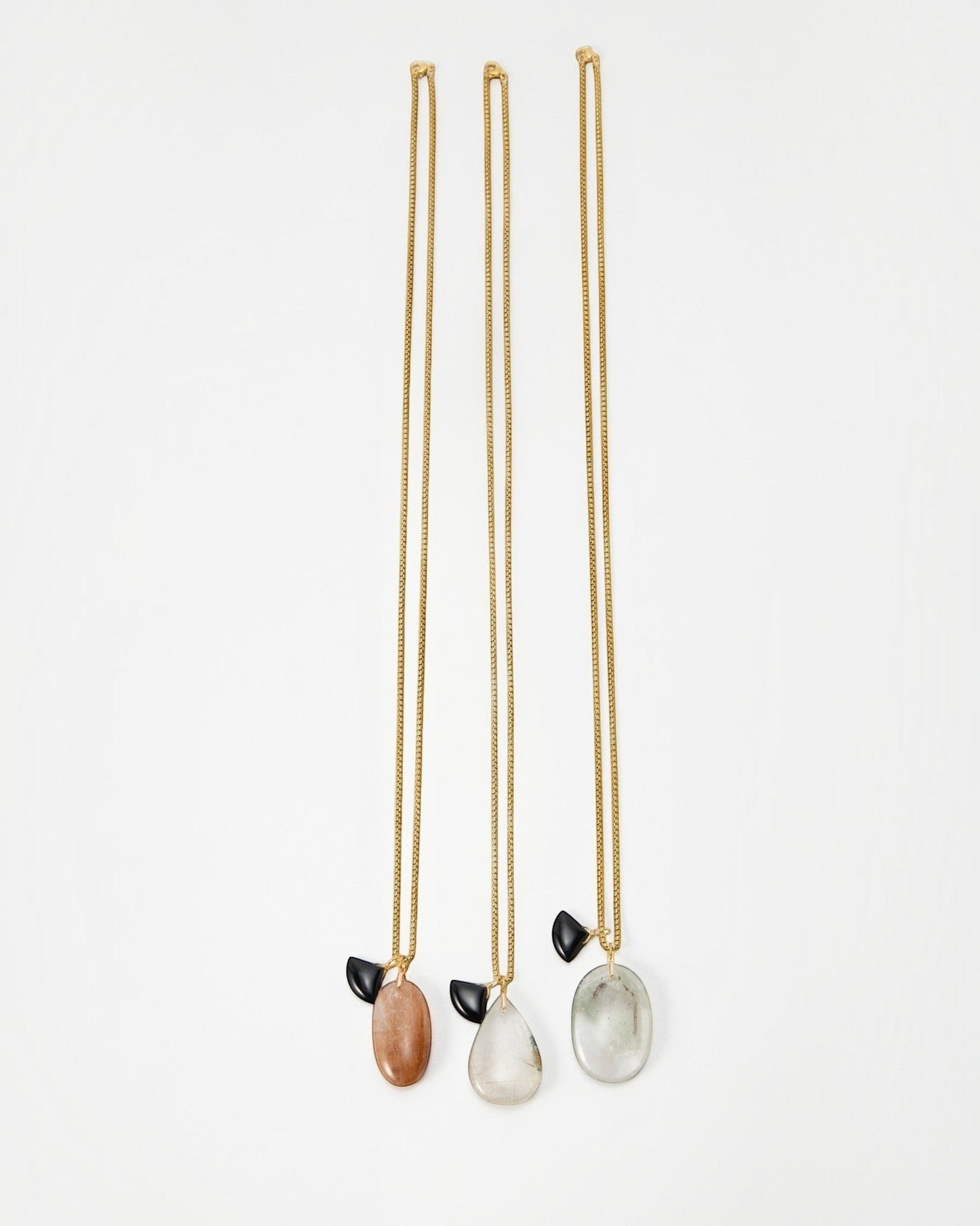 Elsita Jewelry Mist II necklaces featuring gold chains with oval stone pendants and small black accents