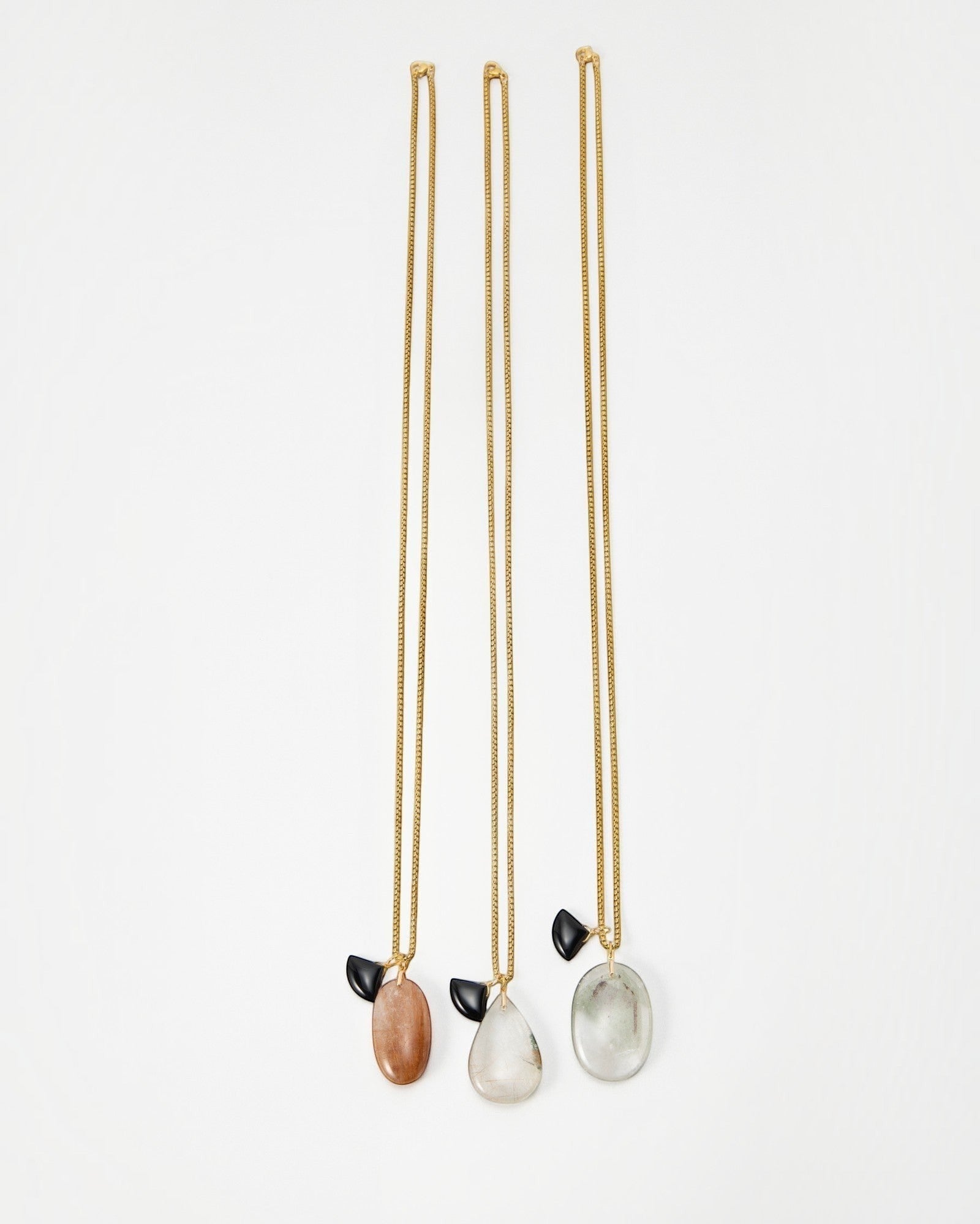 Elsita Jewelry Mist II necklaces featuring gold chains with oval stone pendants and small black accents
