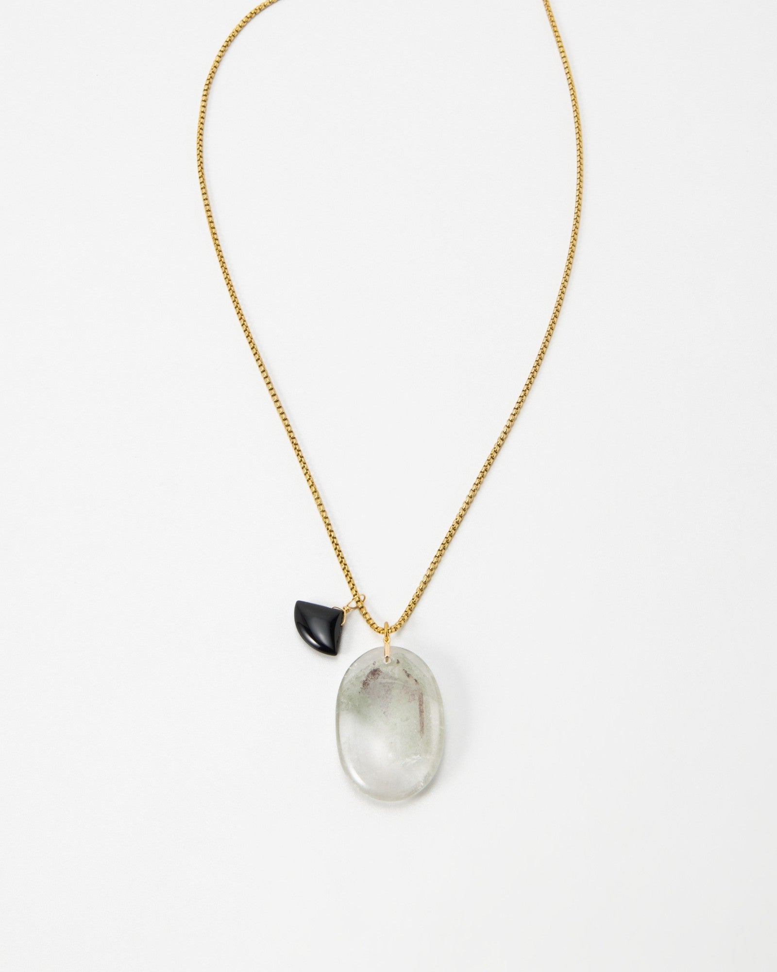 Elsita Jewelry Mist III necklace featuring a large oval translucent stone and a small black charm on a gold chain.
