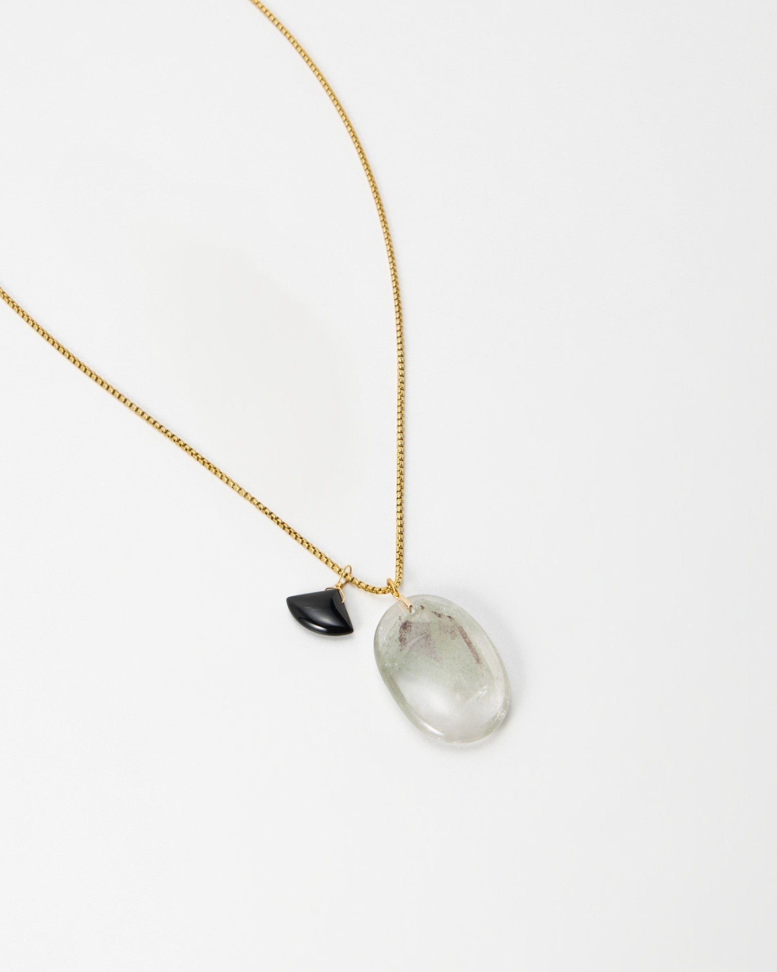 Elsita Jewelry Mist III necklace featuring a gold chain with a clear quartz pendant and a small black accent stone