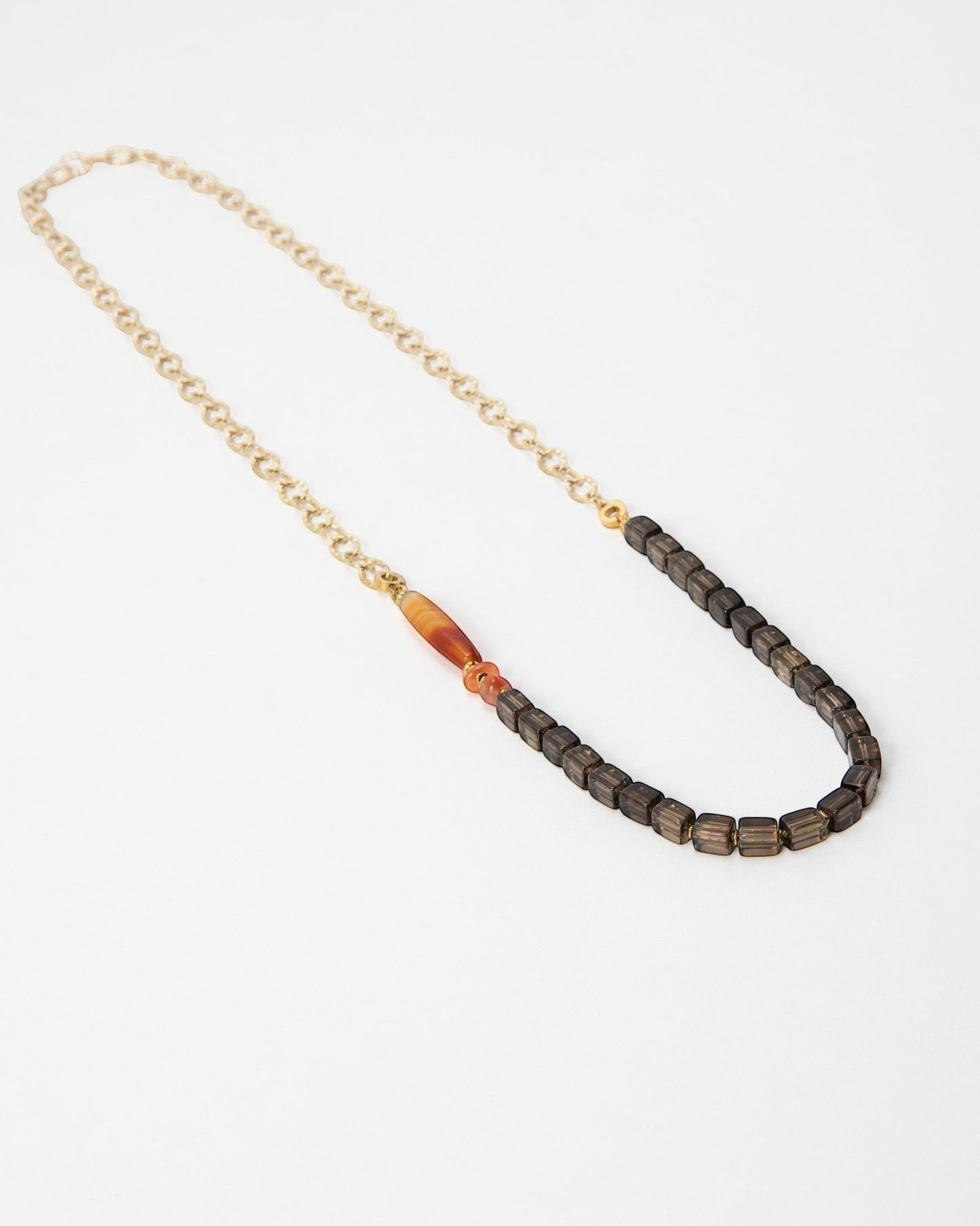 Elsita Jewelry Mosaic necklace featuring a gold chain, dark square beads, and a single orange carnelian accent bead.