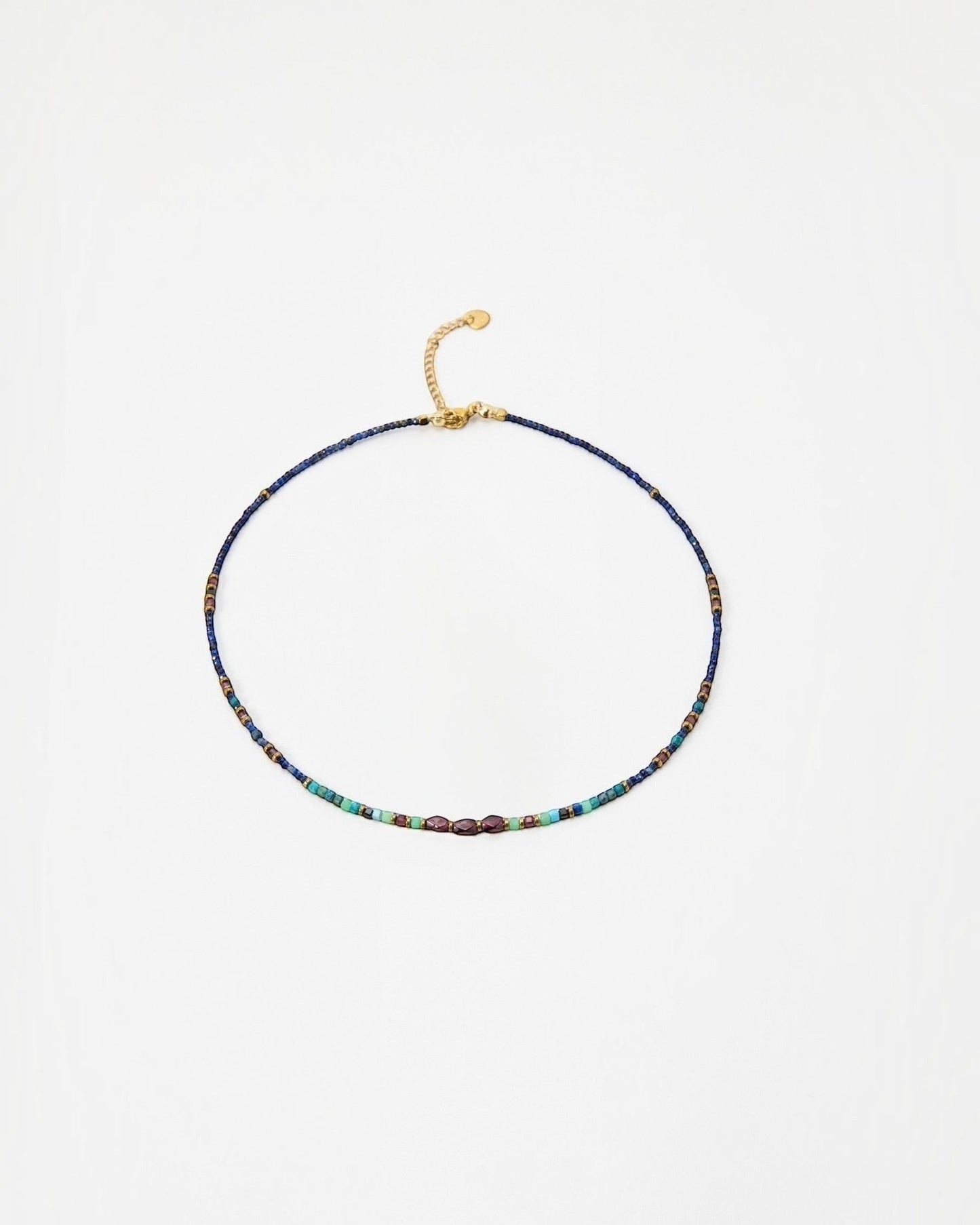 Elsita Jewelry Nomad beaded choker necklace with blue, turquoise, and metallic accents on a gold-tone chain.